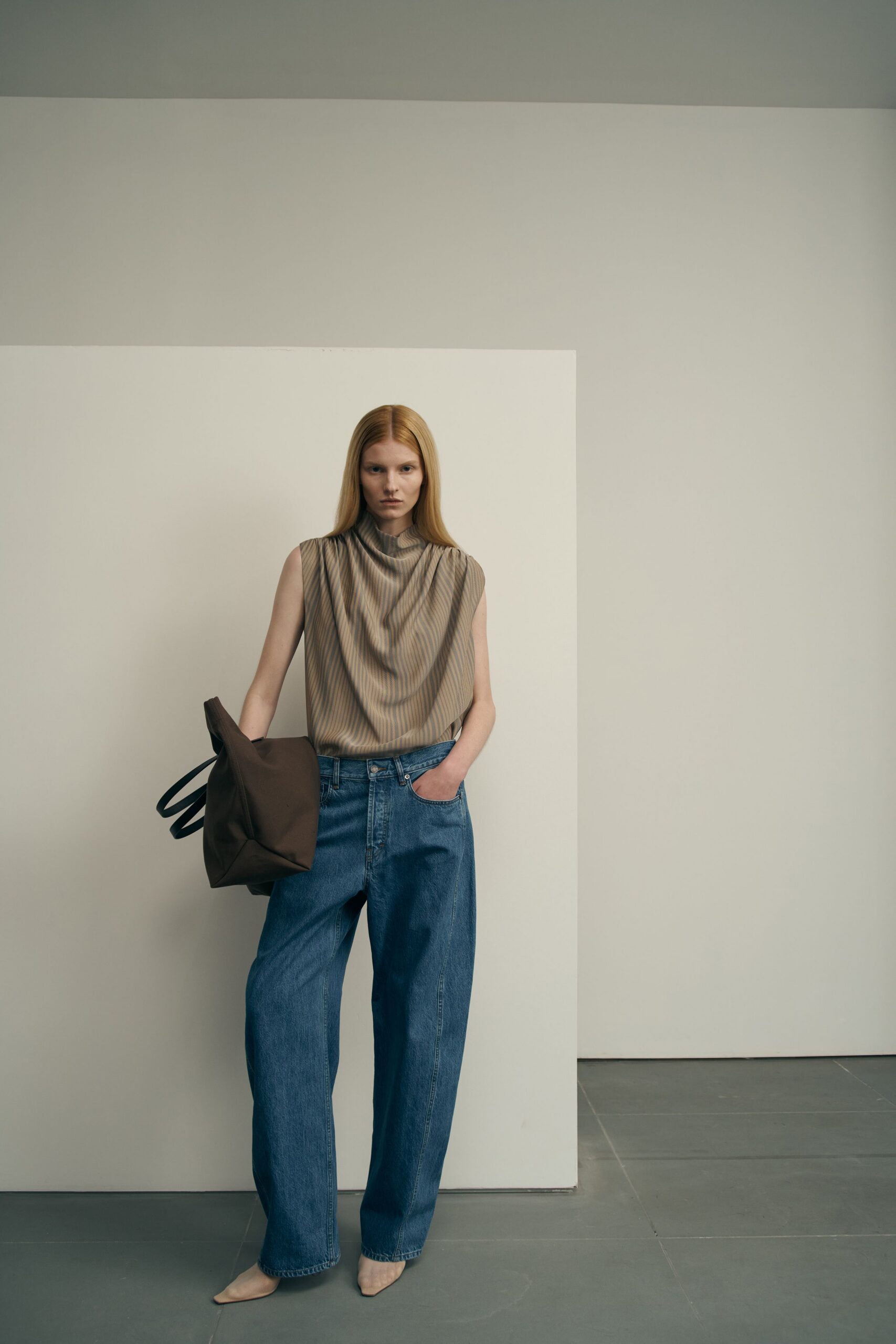 beige pleated sleeveless top with wide-leg jeans