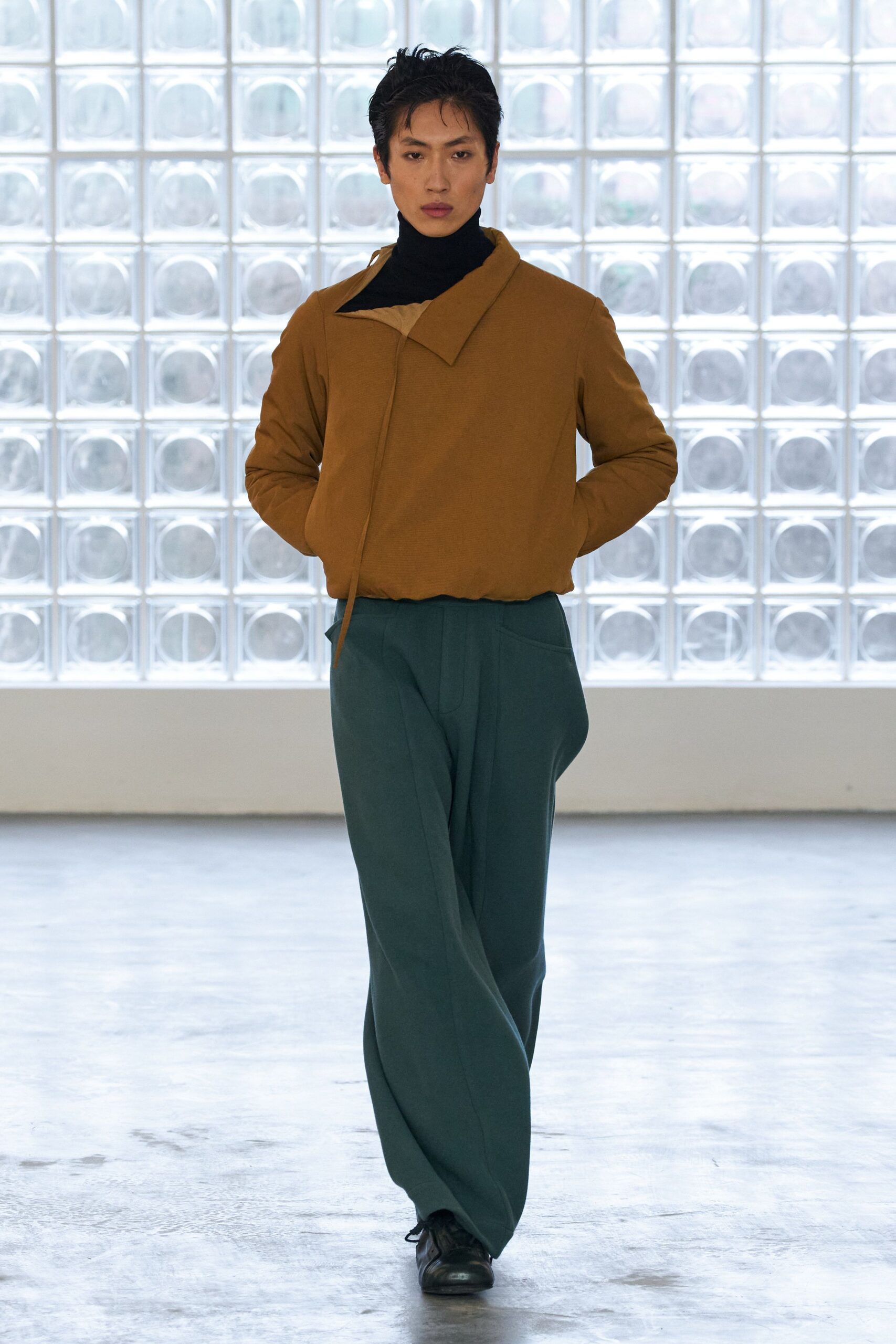 brown jacket black turtleneck green pants