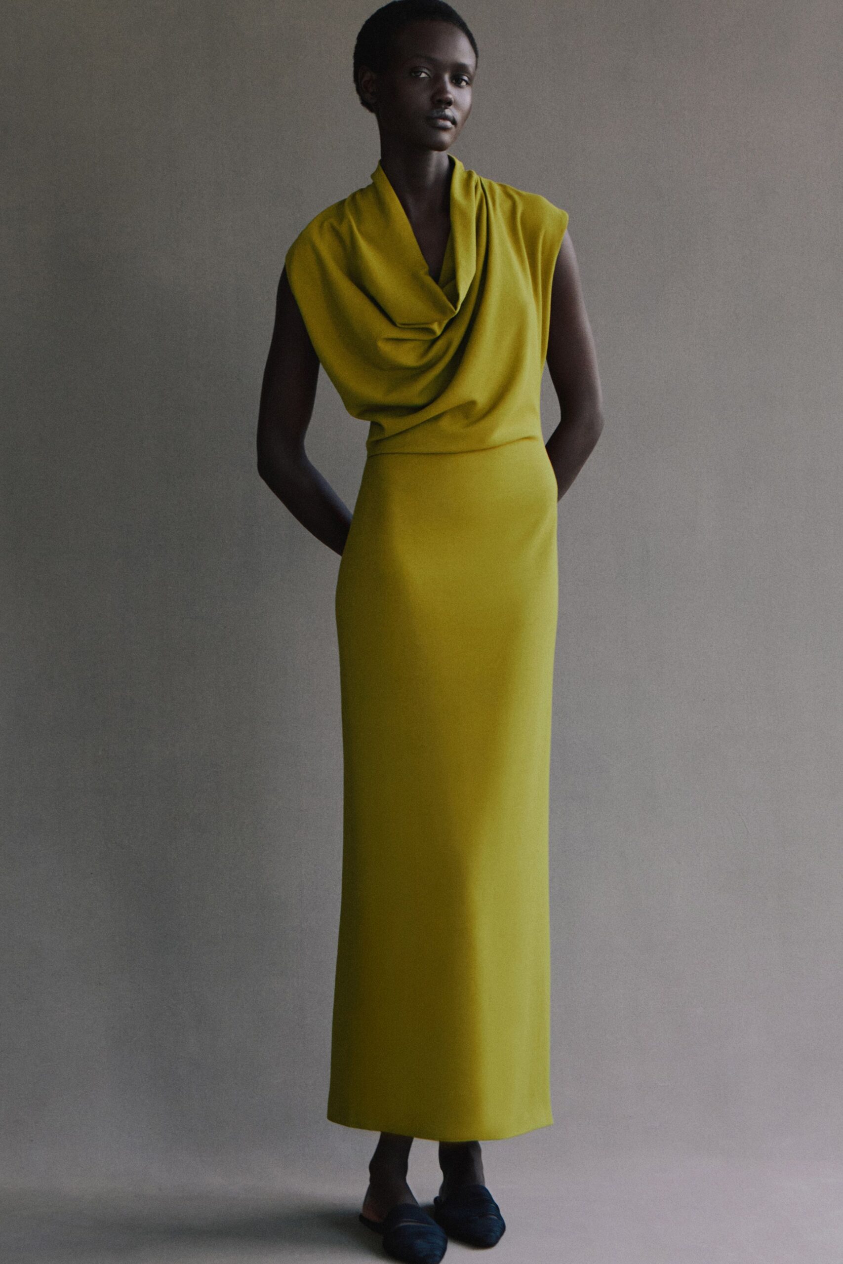 yellow silk draped gown with black shoes
