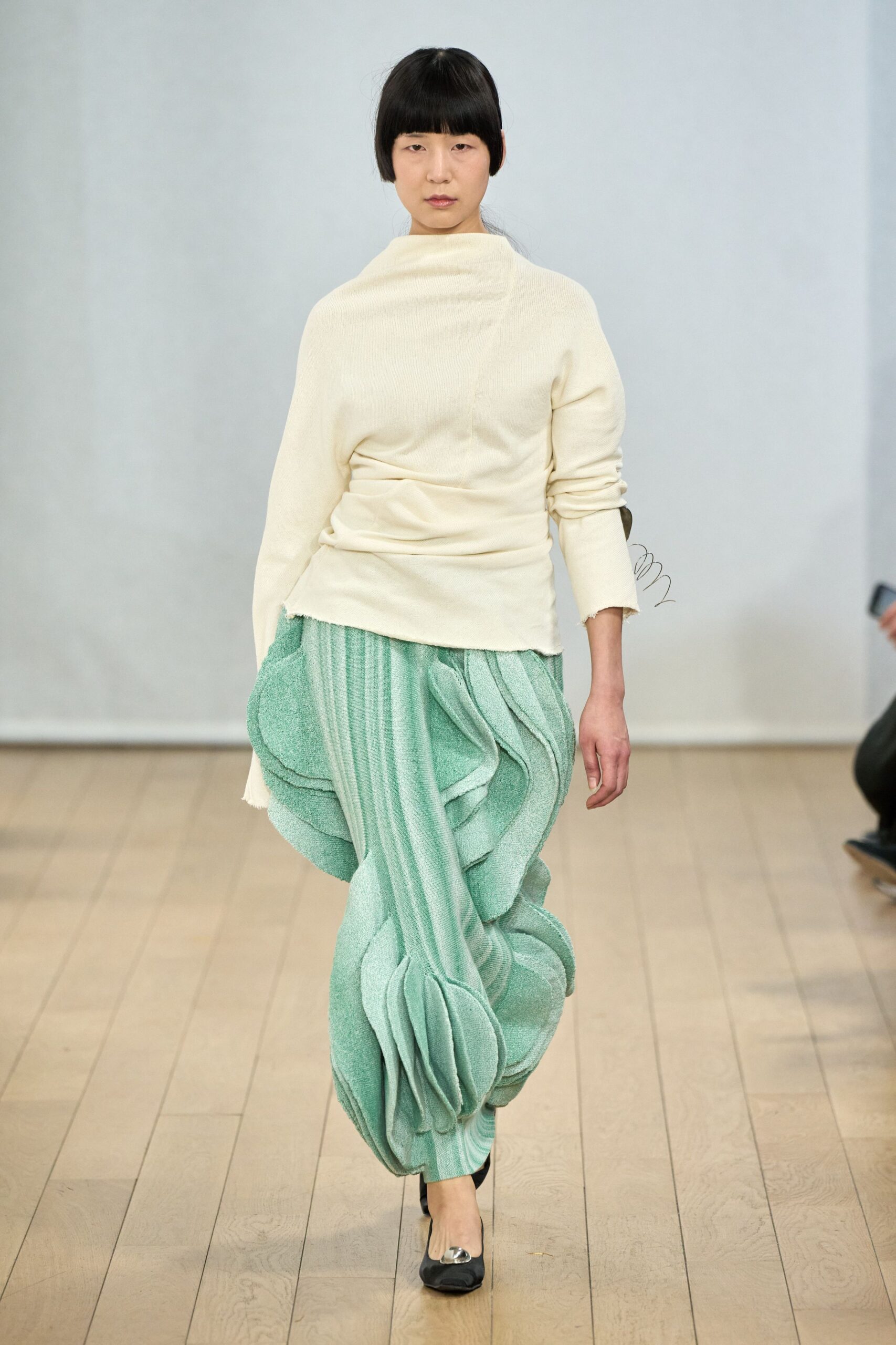white relaxed top with green pleated pants