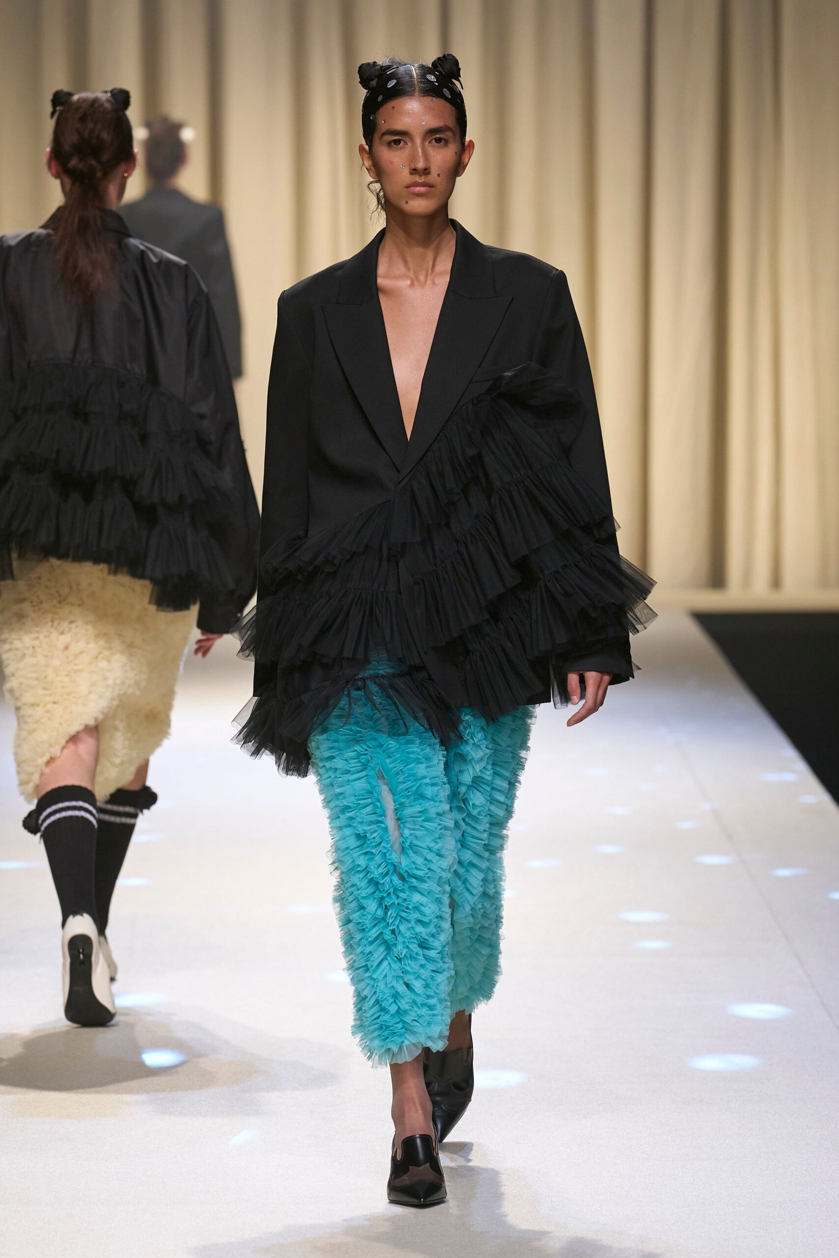 black ruffled blazer with blue fringed pants