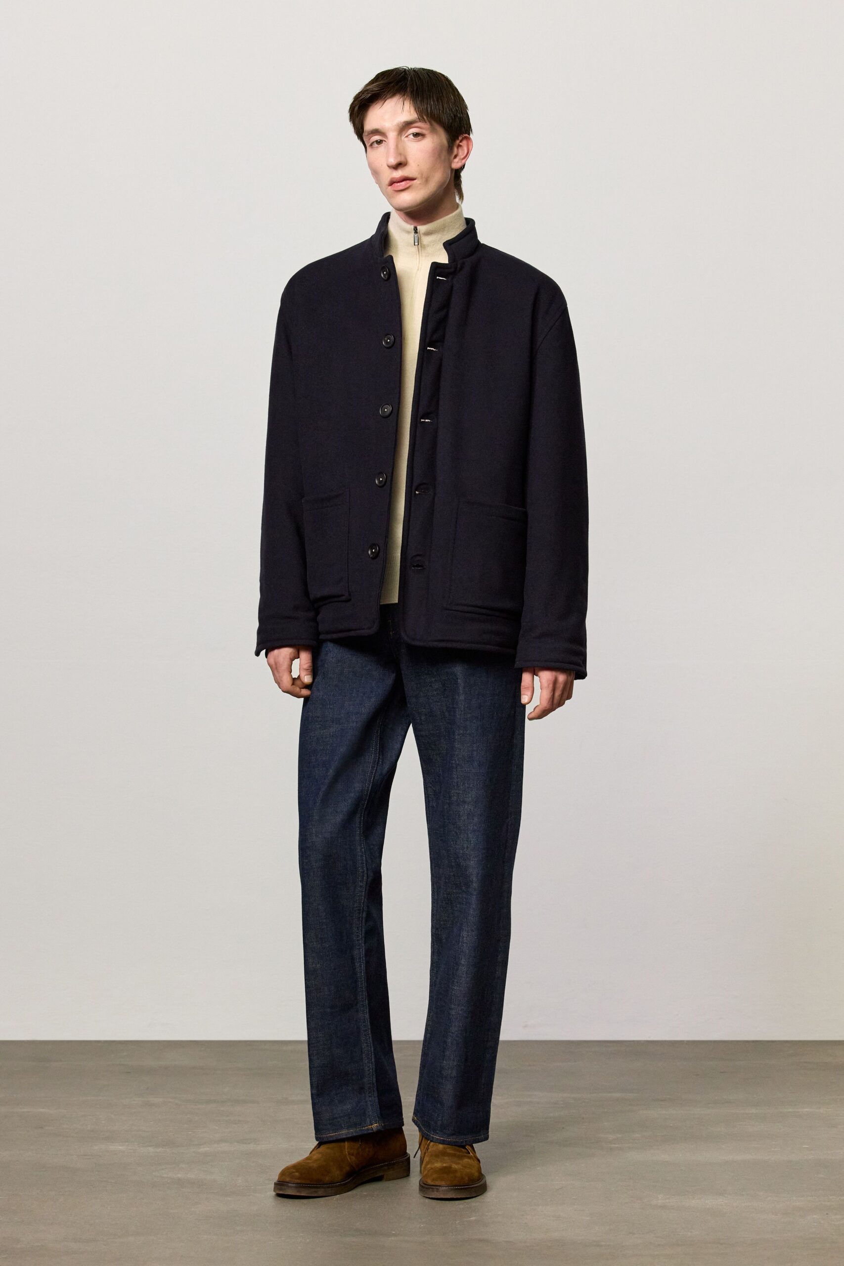 black jacket beige turtleneck blue pants brown shoes