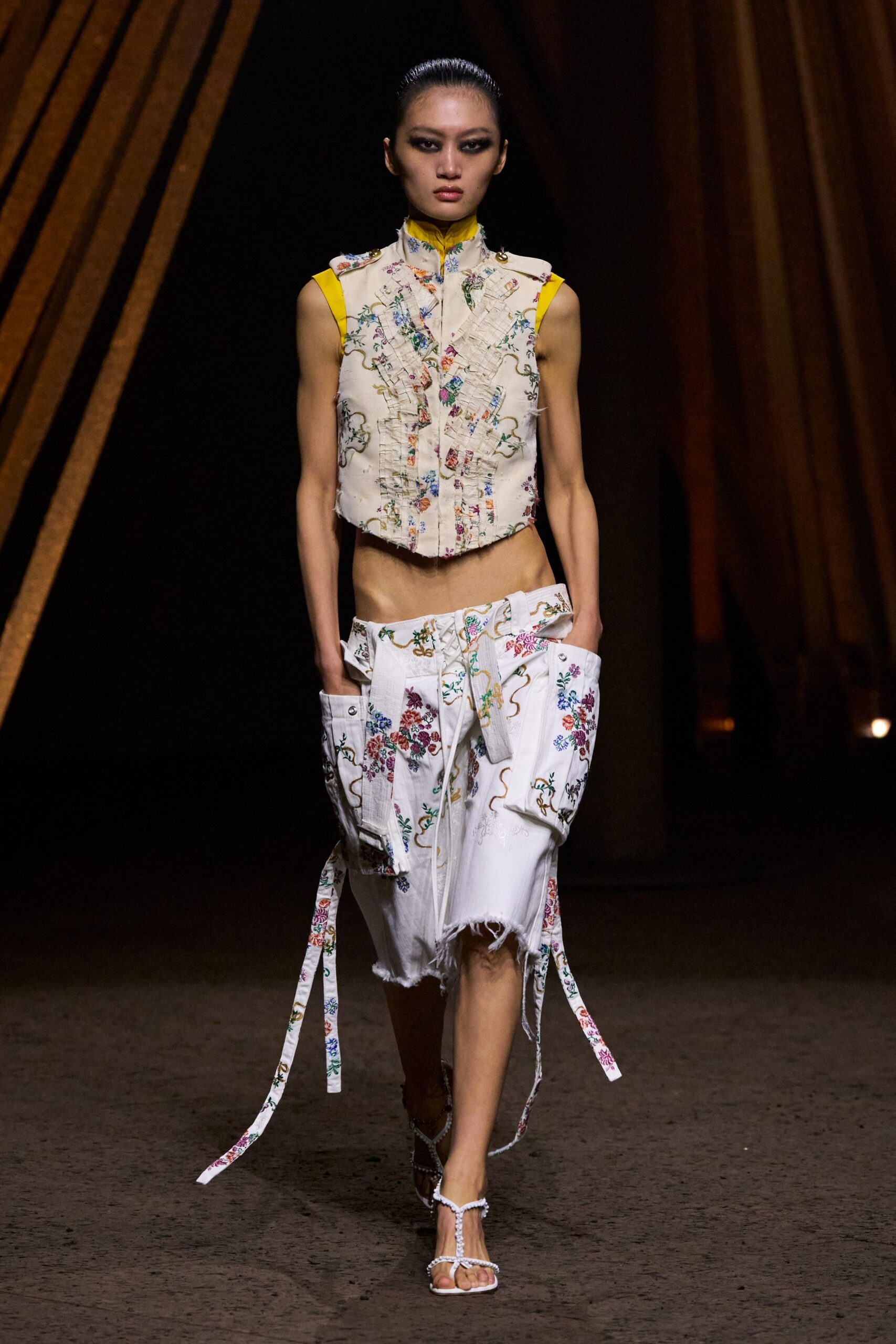 beige embroidered sleeveless top with white pants