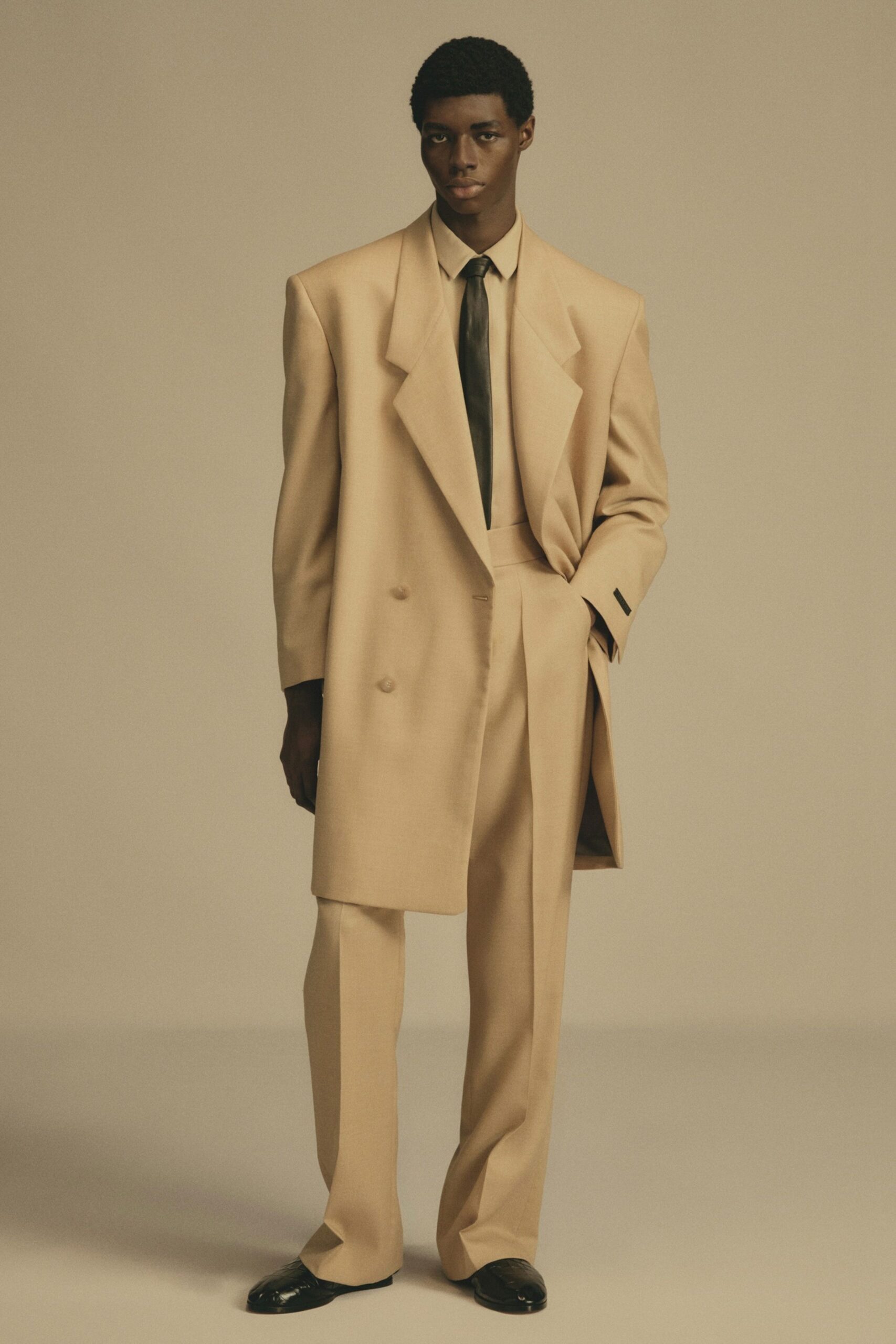 beige tailored suit with black tie