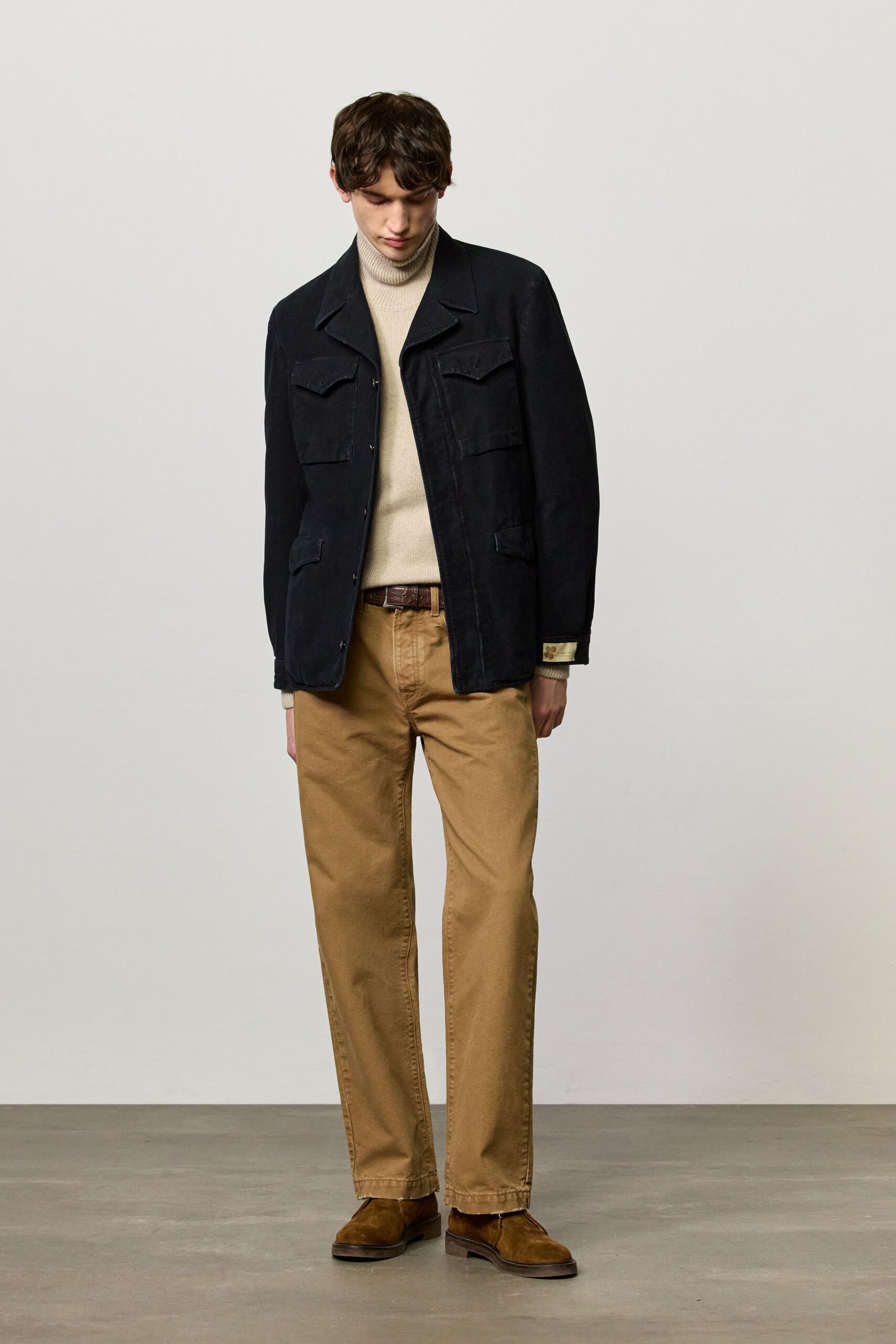 black jacket beige sweater tan pants