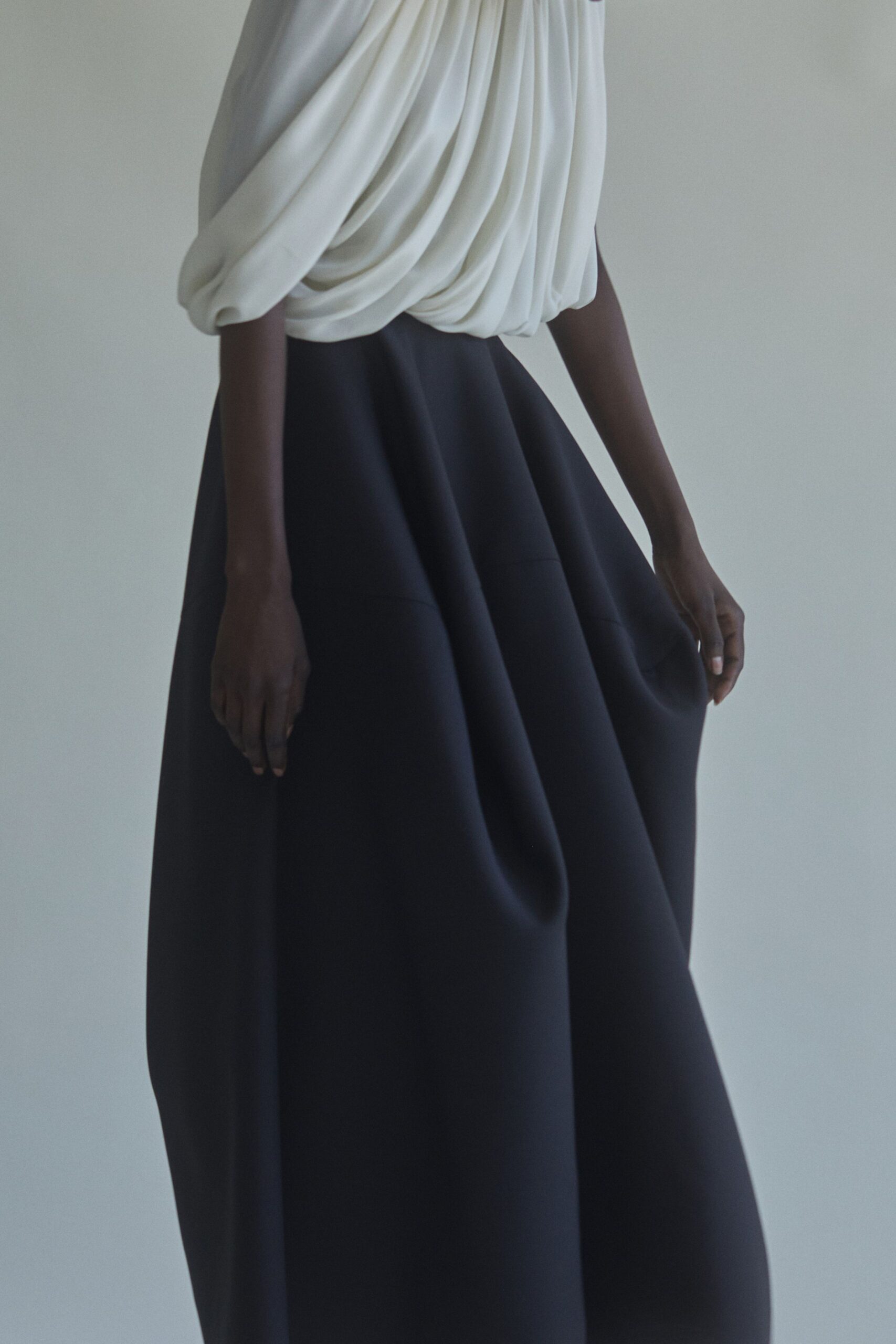 white draped top and black pleated skirt