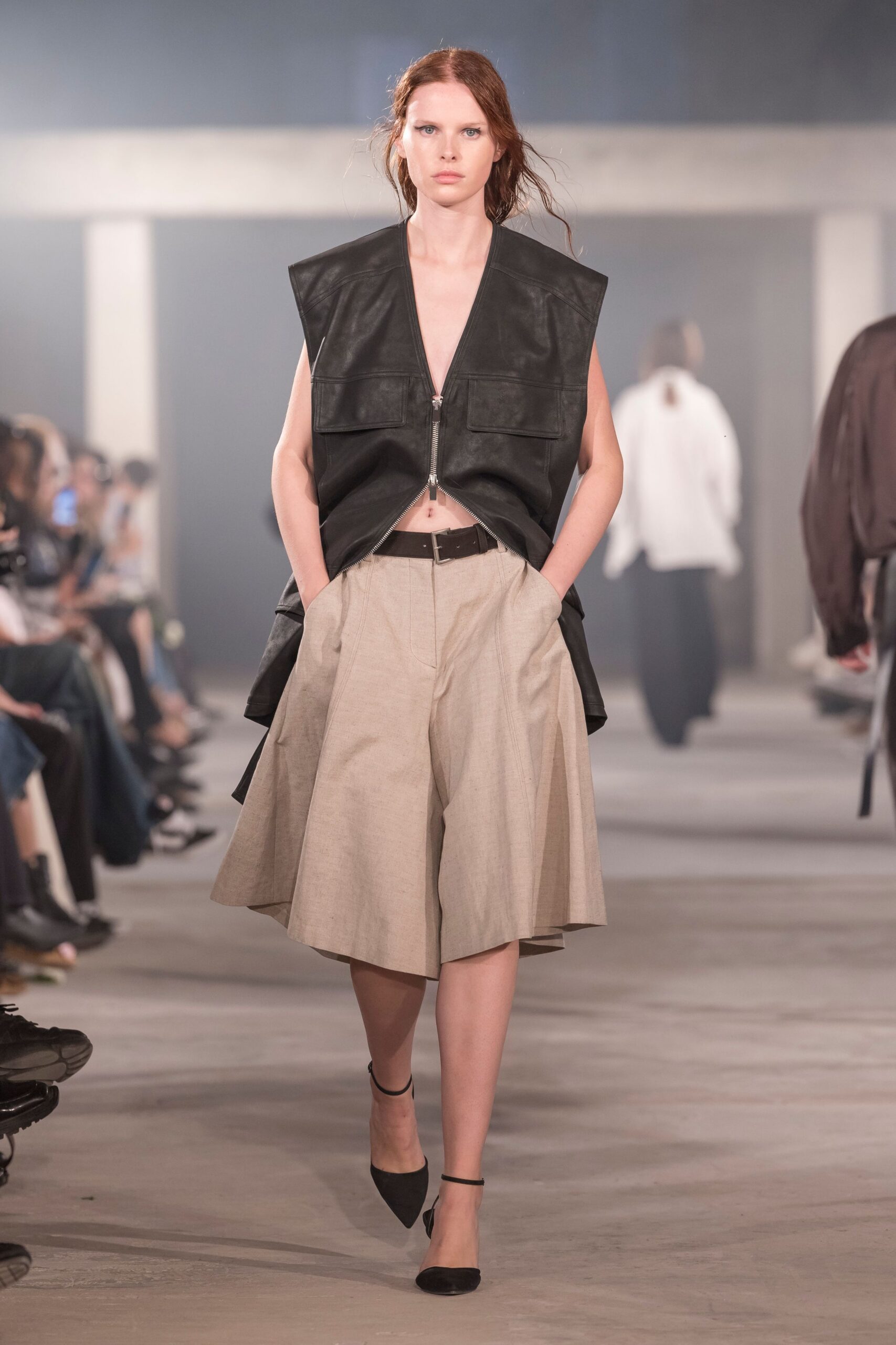 black leather sleeveless top with beige pleated skirt