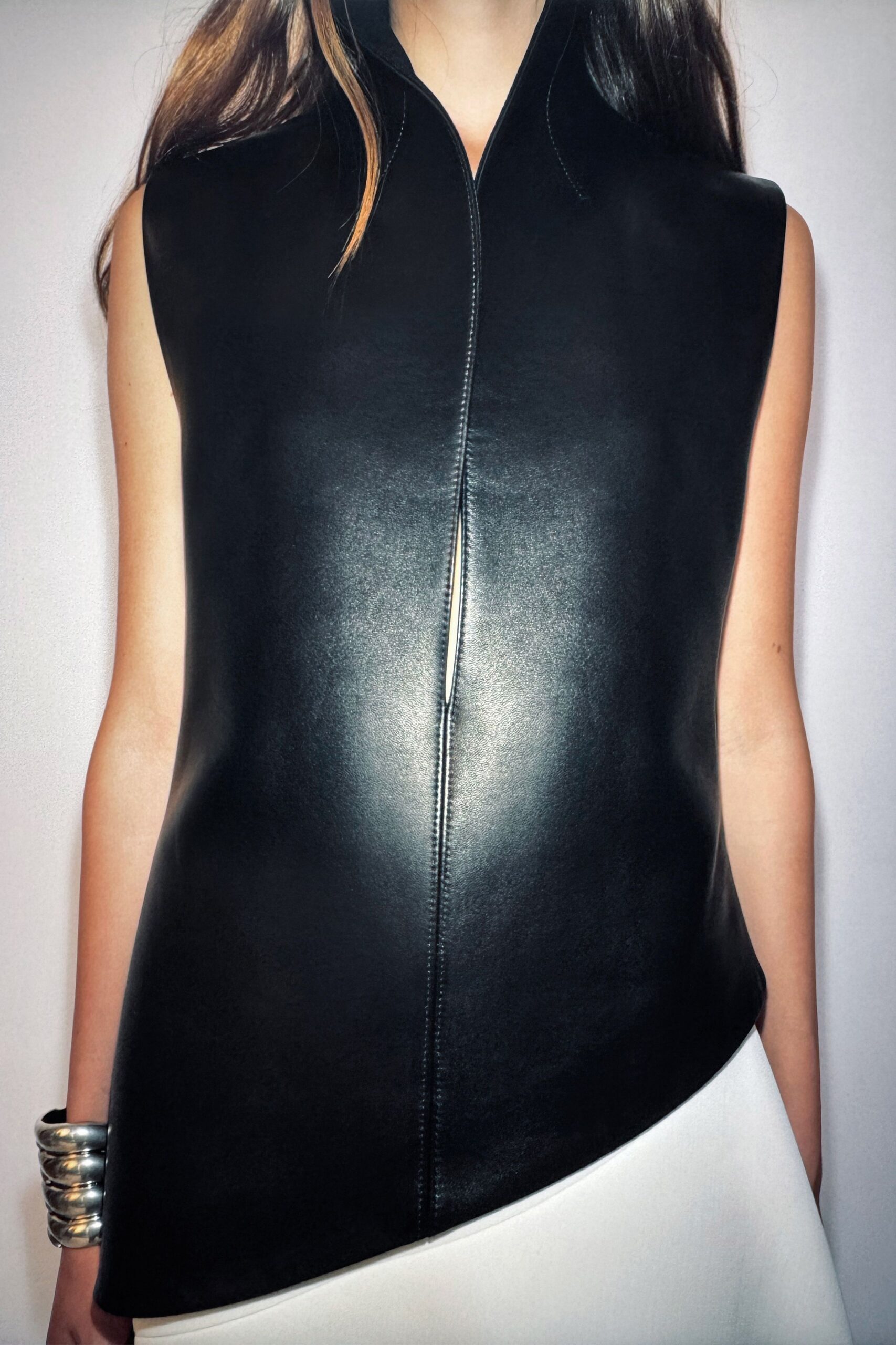 black leather sleeveless top and white skirt