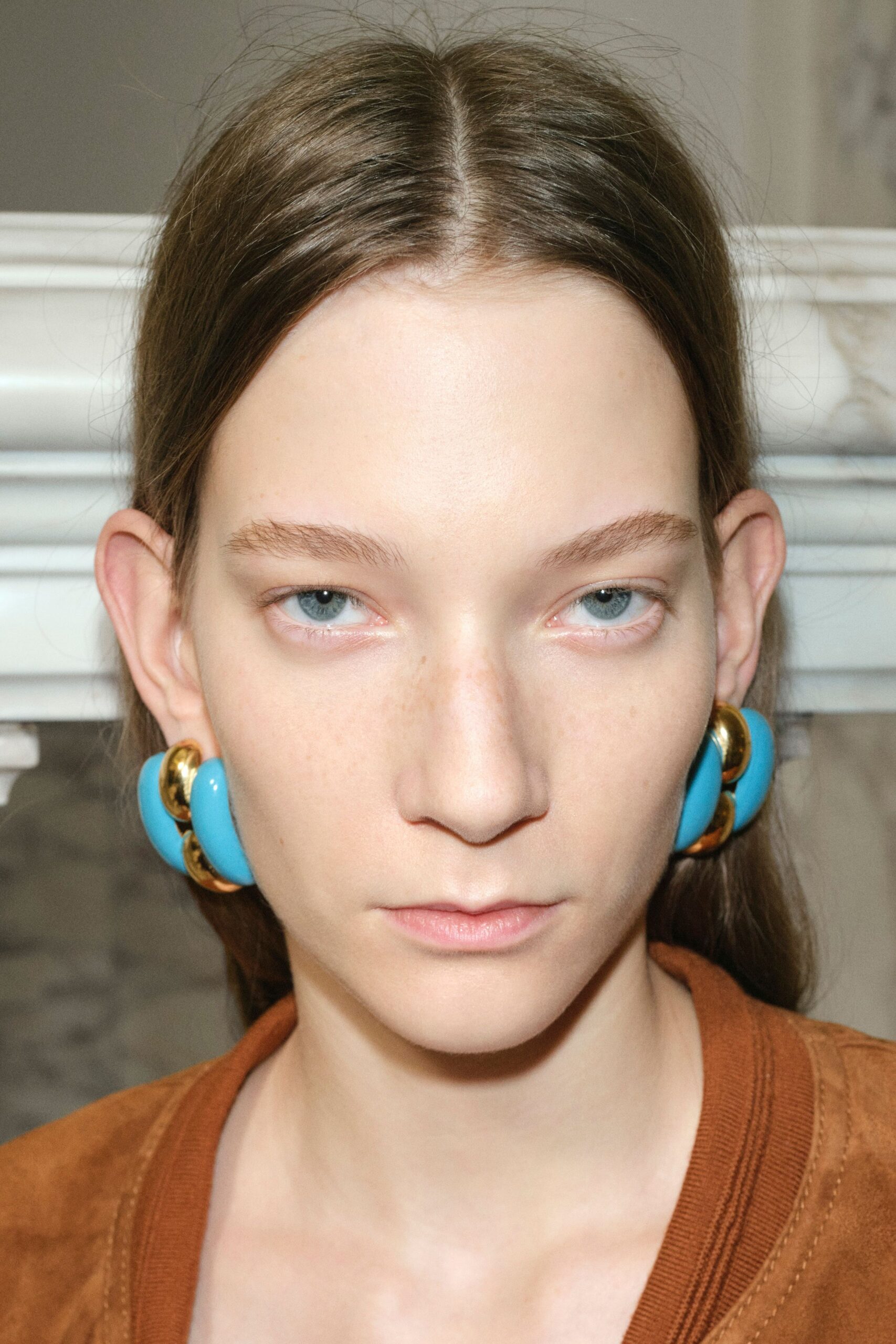 brown relaxed jacket with blue earrings
