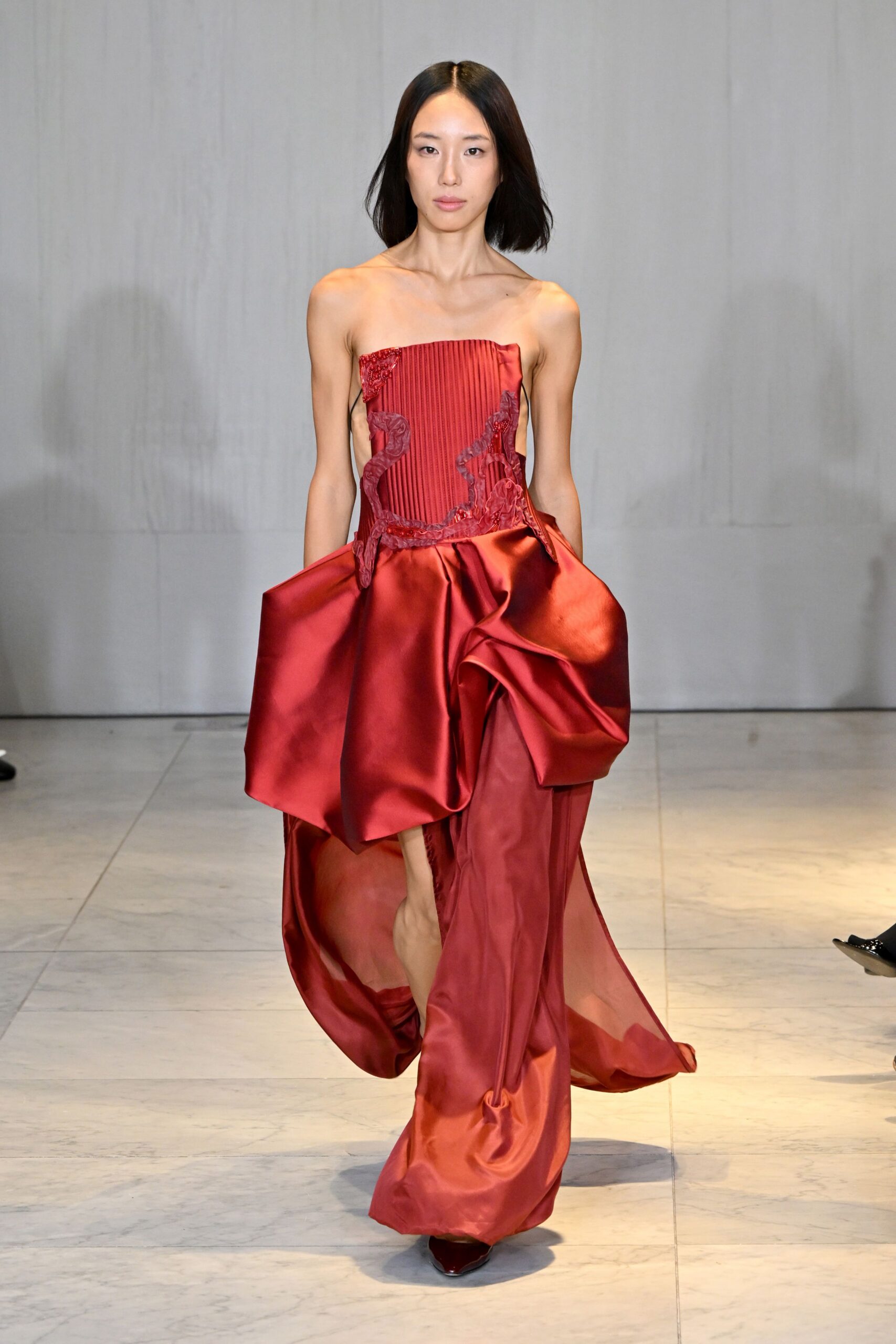 red silk strapless fitted pleated draped flowing gown
