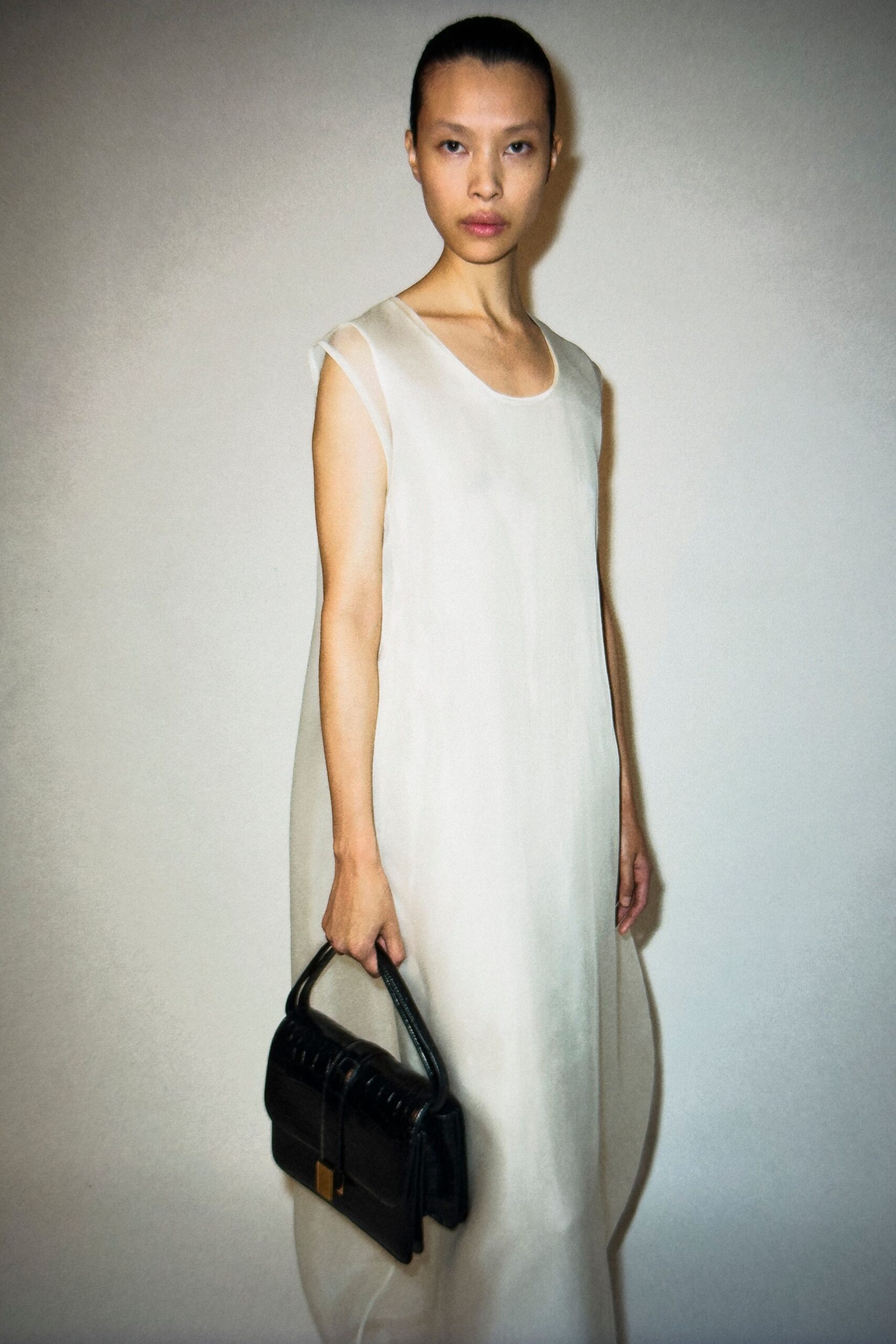 white silk sleeveless dress with black bag