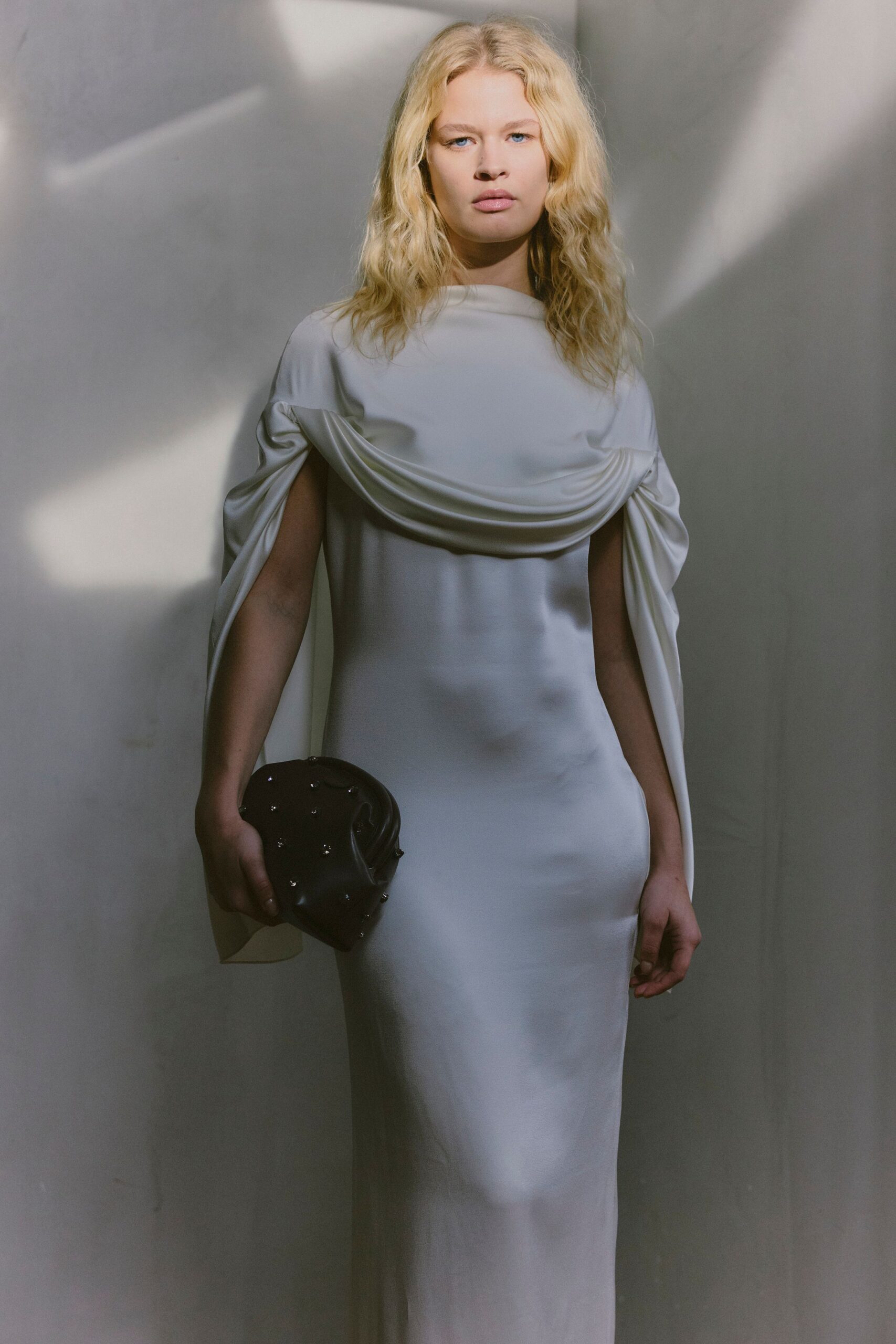 white silk draped gown with black bag