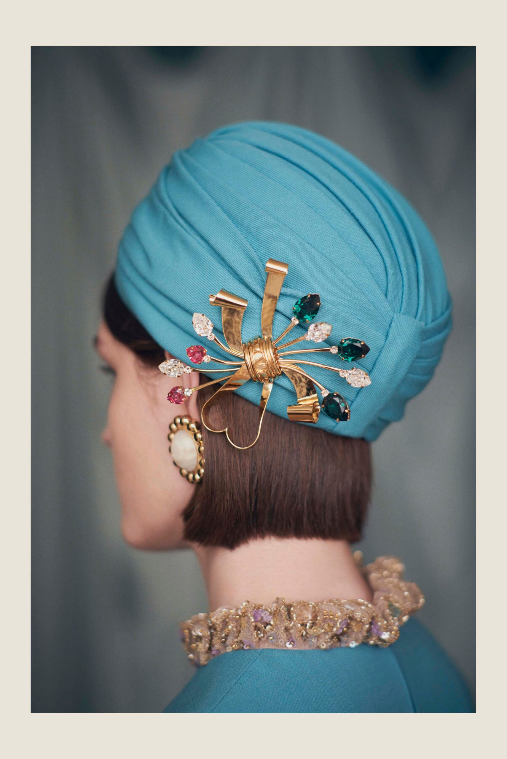 blue pleated hat with gold necklace