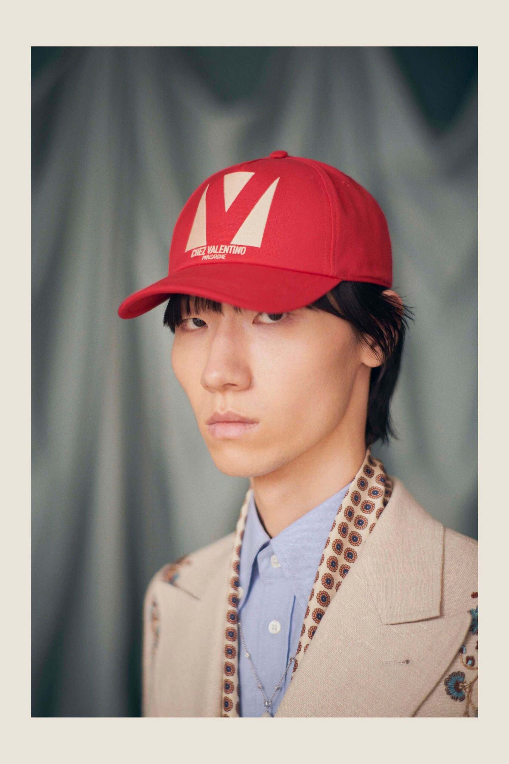 beige tailored blazer with blue shirt and red cap