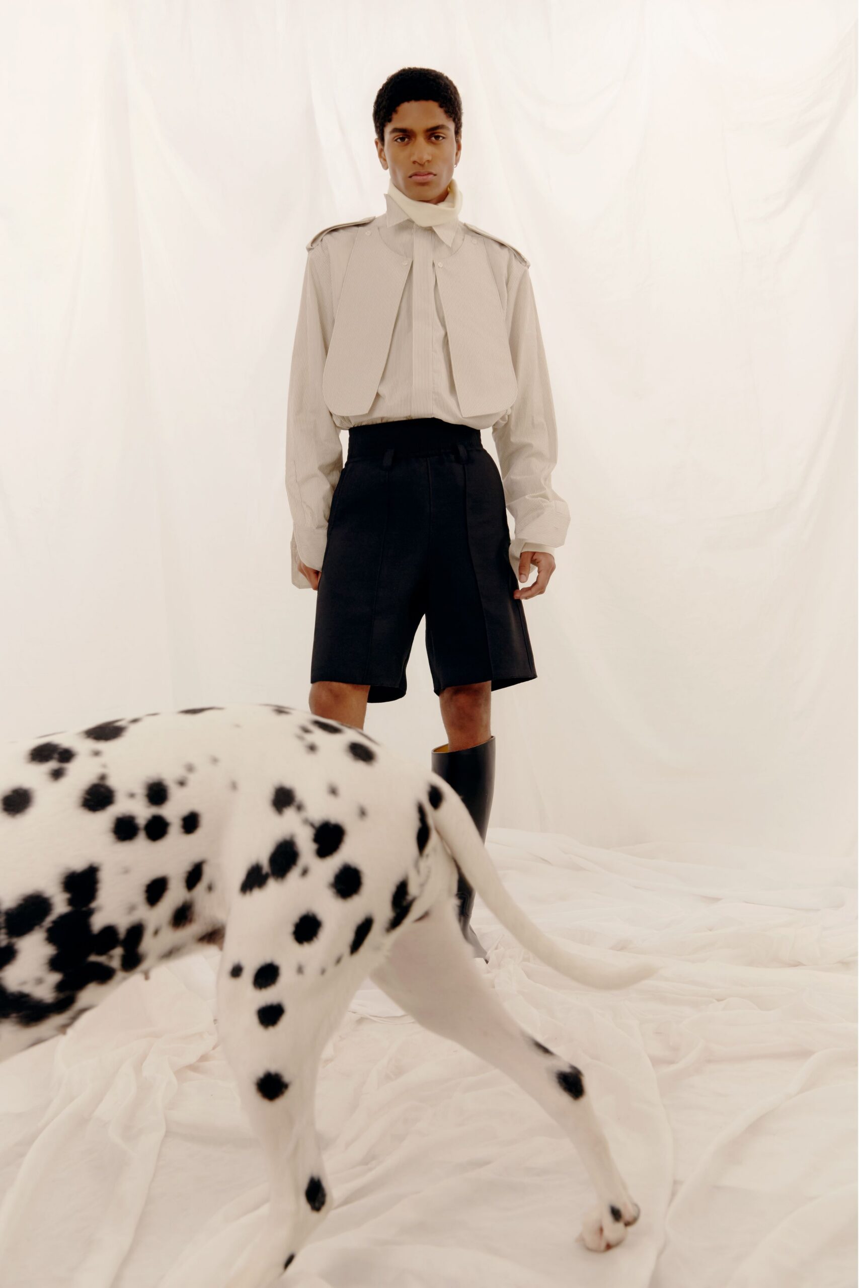 white shirt beige vest black shorts