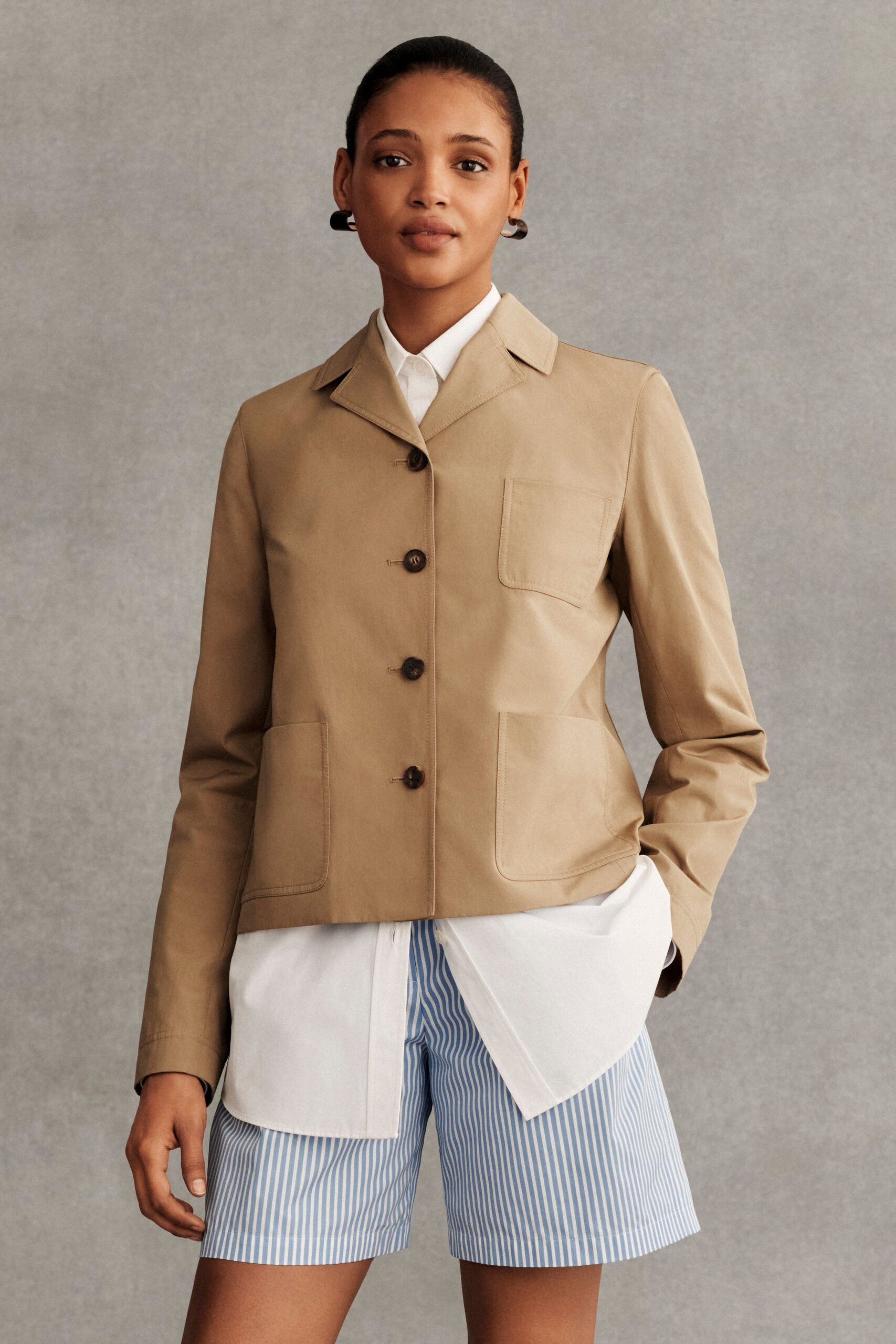 beige jacket with white shirt and blue striped shorts