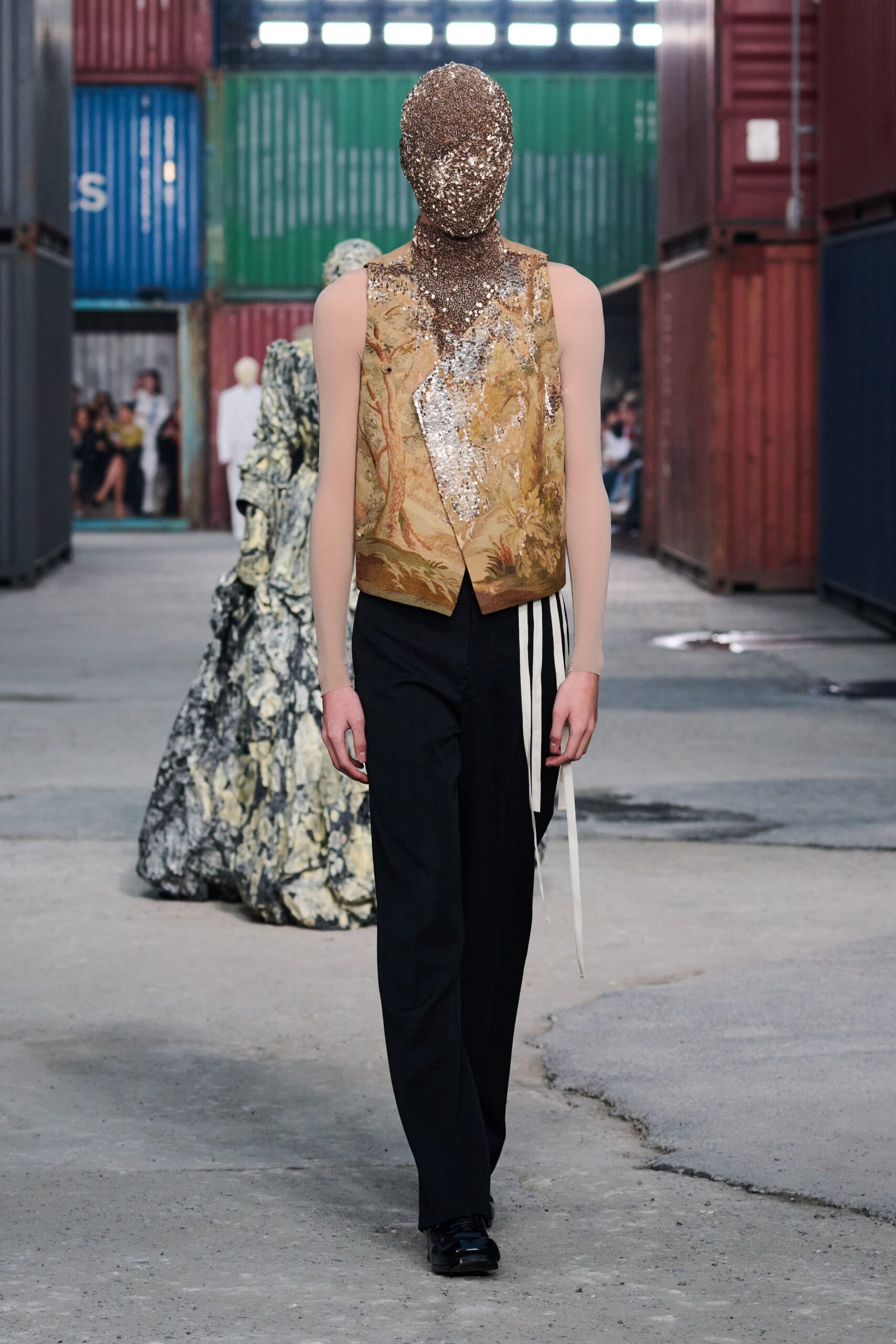 gold embroidered sleeveless vest and black pants