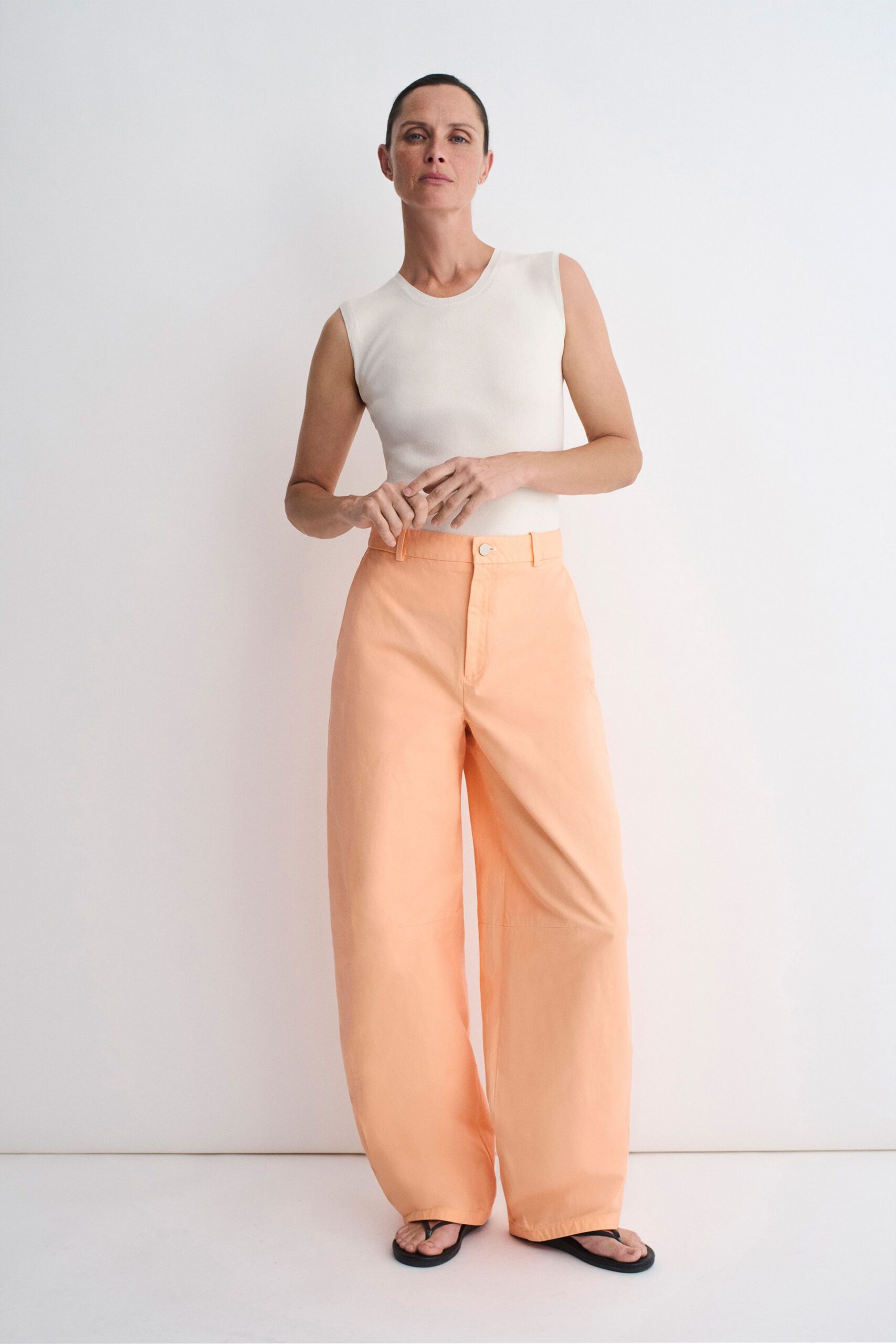 white fitted top with orange pants