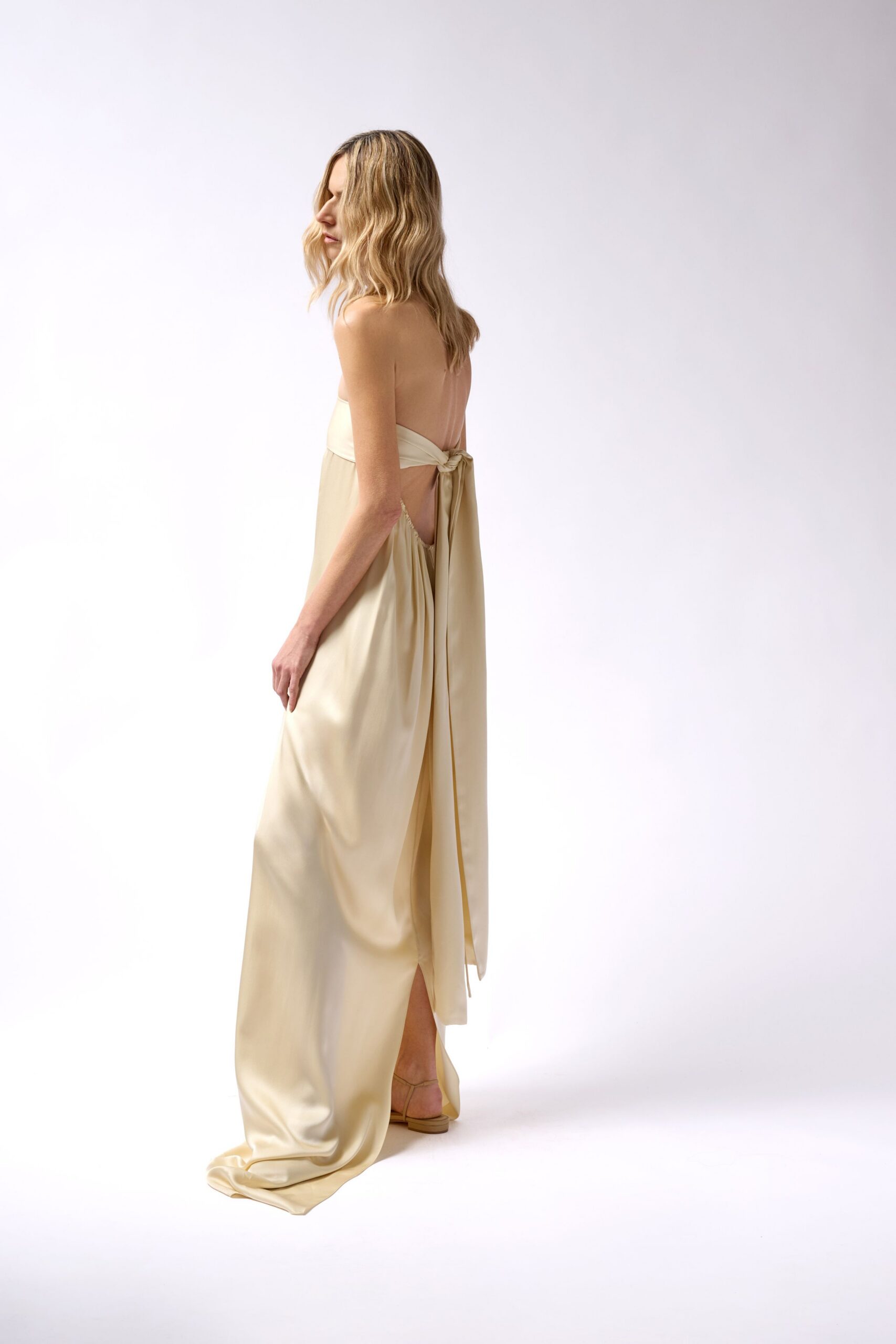 beige silk sleeveless backless fitted draped flowing gown