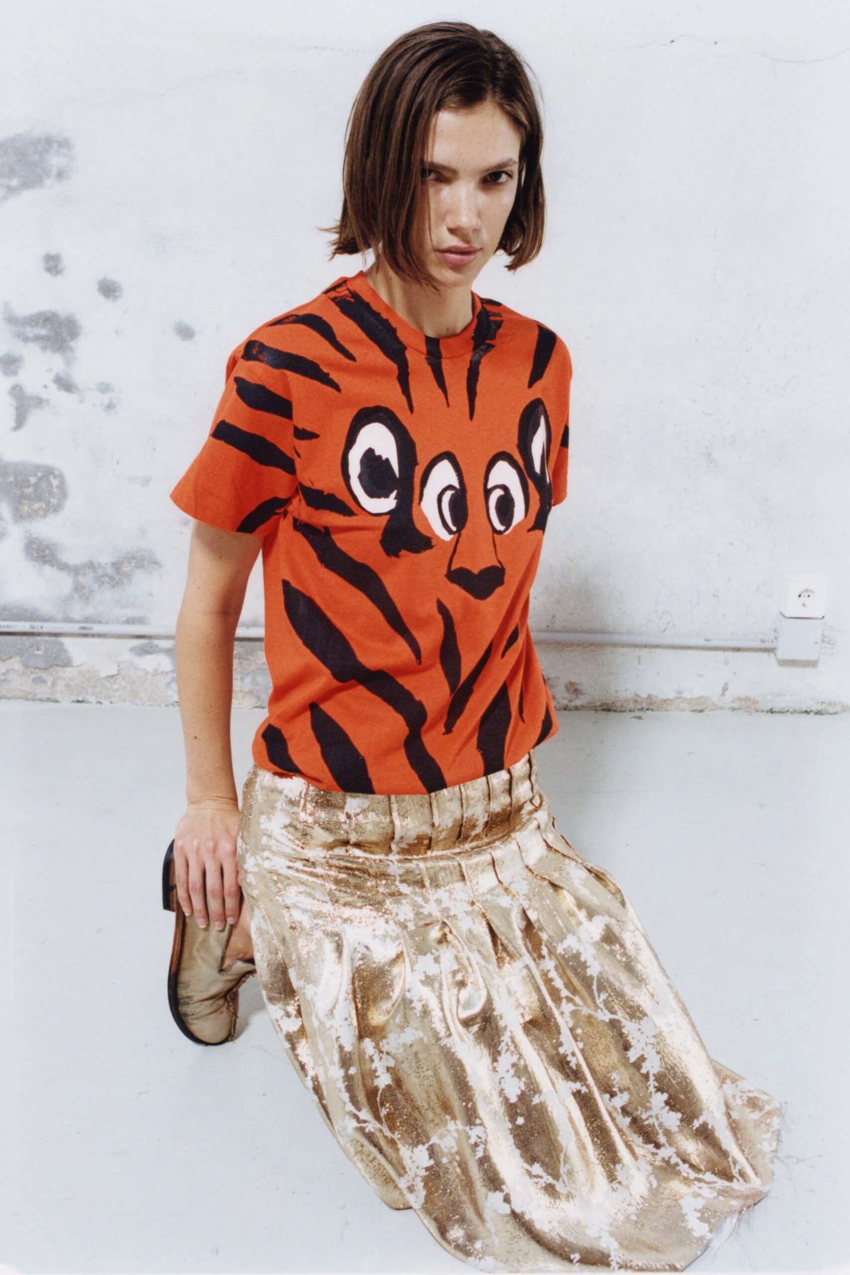 orange printed t-shirt with gold pleated skirt