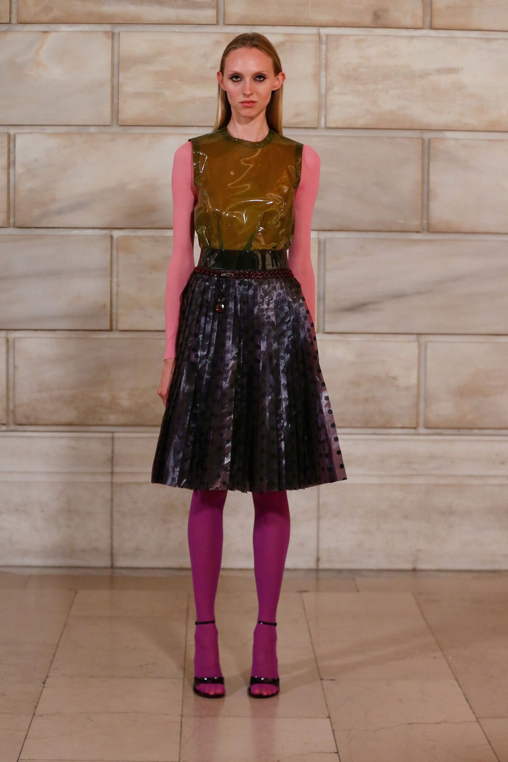 green vinyl sleeveless top and black pleated skirt