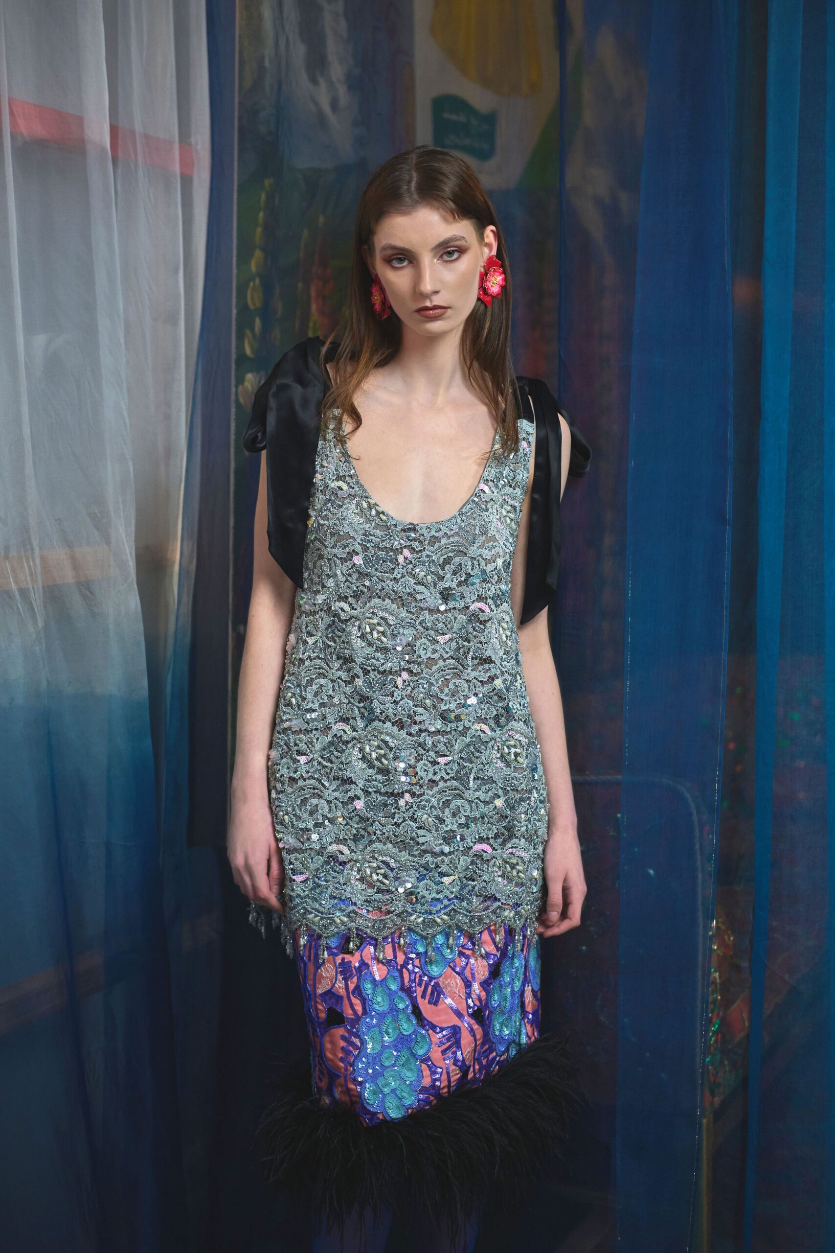 Pale silver lace slip dress crusted with sequins, a black satin bolero slipping off the shoulders, and a hem banded in inky marabou over cobalt-and-coral beaded panels. Waiting behind a theater curtain that smells faintly of dust.