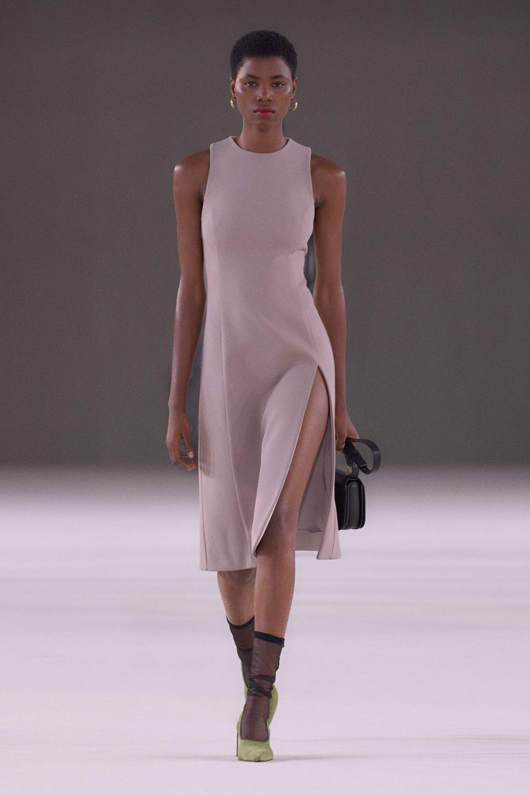 Pale dove sleeveless sheath, cut in dense crepe with a thigh-high slit. Small hammered gold hoops. Black box bag on a broad strap. Sheer smoke ankle socks. Chartreuse satin pumps with square toes. Walking into a courthouse wedding with rain still on the pavement.