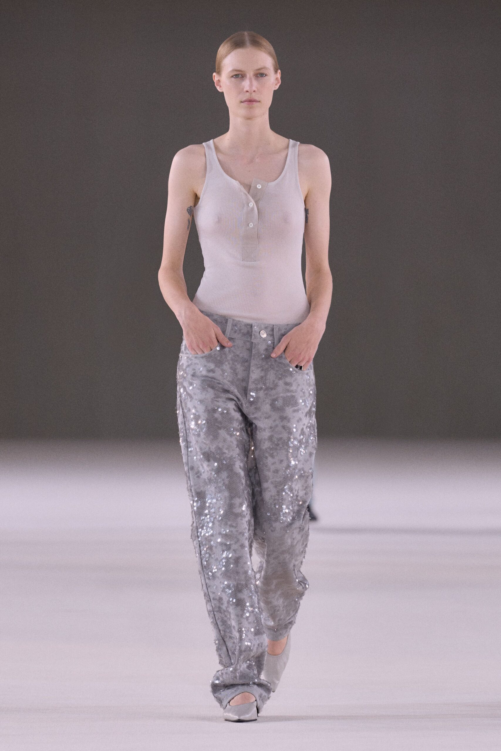 Pale grey ribbed tank, sheer through the buttoned half placket. Clouded silver trousers scattered with sequins, hems dragging into folds. Powder grey peep-toe heels. Walking the hotel corridor at dawn after washing glitter from your hands.