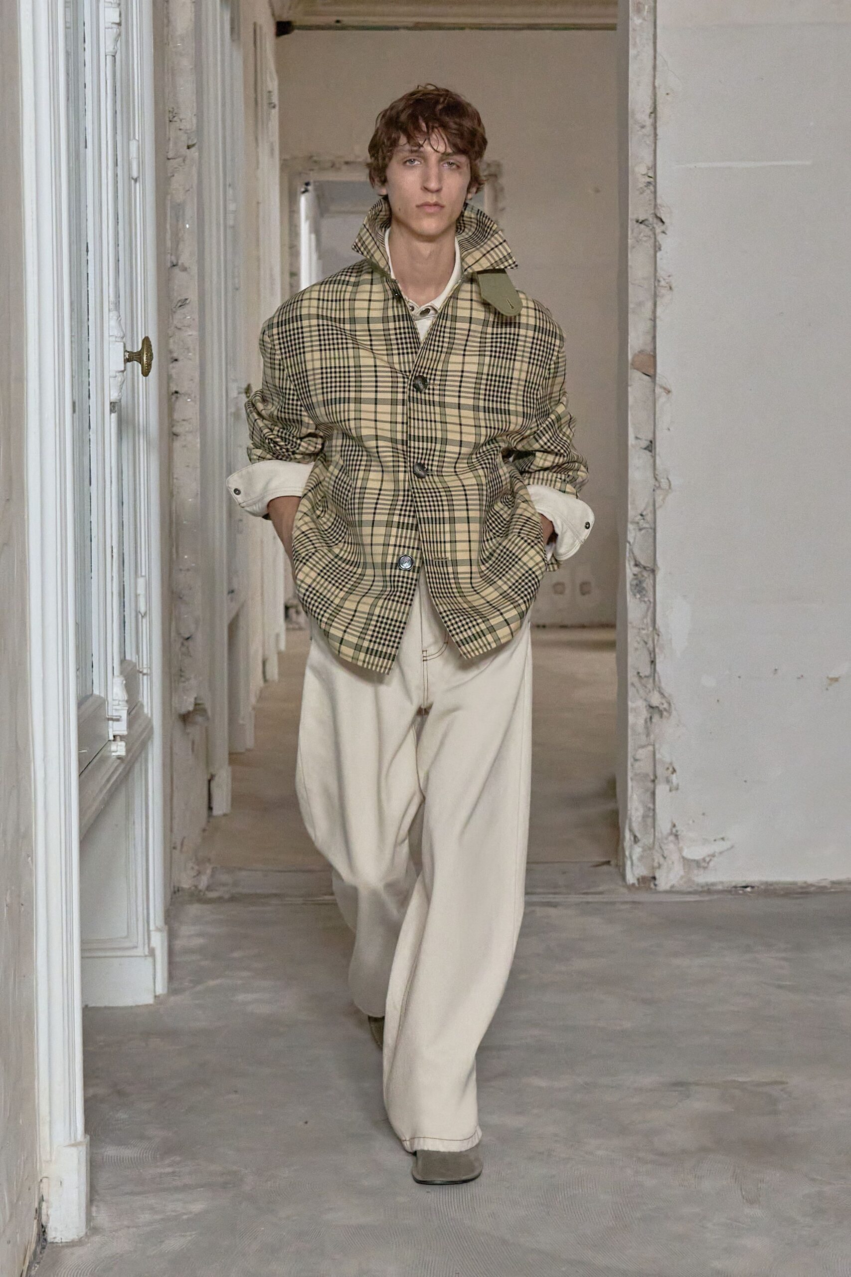 Beige plaid jacket with a popped collar and scrunched sleeves. Cream henley peeking through with two small neck buttons. Wide ivory trousers in a dense twill, breaking over the shoe. Dusty olive square-toe shoes. Walking through an unfurnished apartment before the plaster dust settles.
