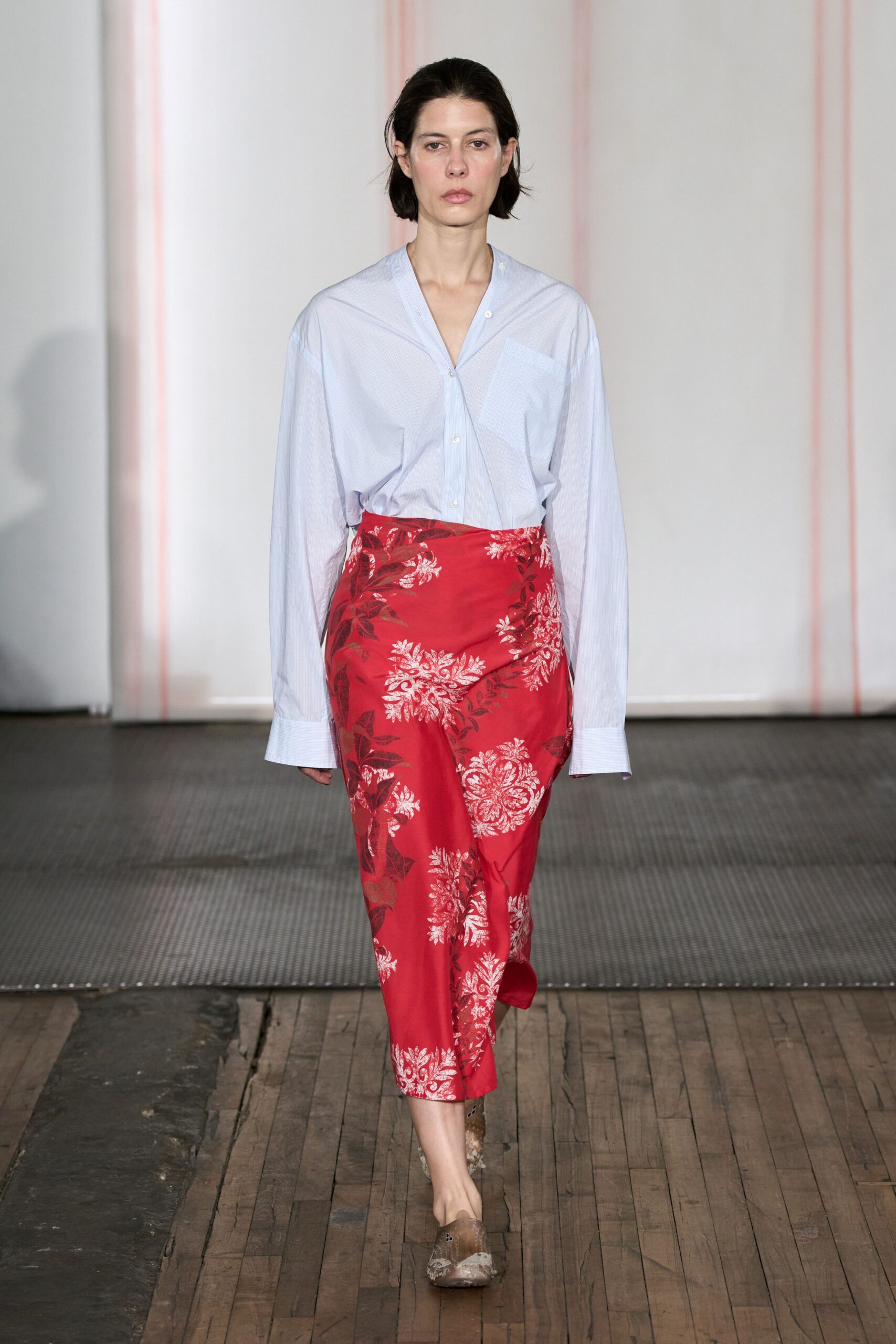 Pale blue pinstriped cotton shirt, off-center placket folding into a deep V. Red satin wrap skirt with silver floral brocade and a skewed overlap. Mottled taupe flats, square at the toe. Walking across old floorboards after spilling tea on the good tablecloth.