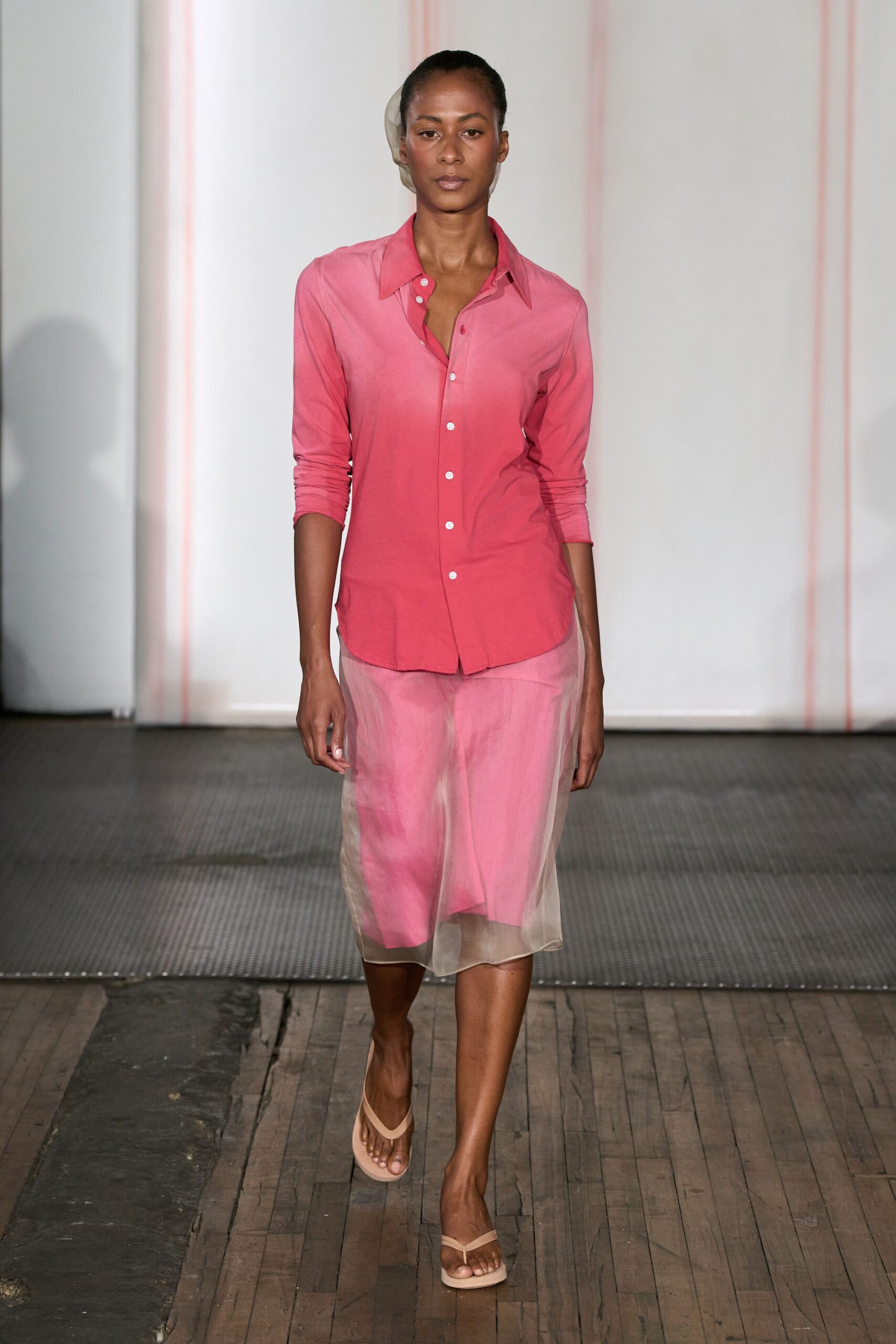 Coral jersey button-down fading lighter at the shoulders, third button undone. Sheer oyster organza tube over a hot-pink slip, hem hitting the calf. Nude thong sandals with squared soles. Walking back from the beach club before the terrace fills for lunch.
