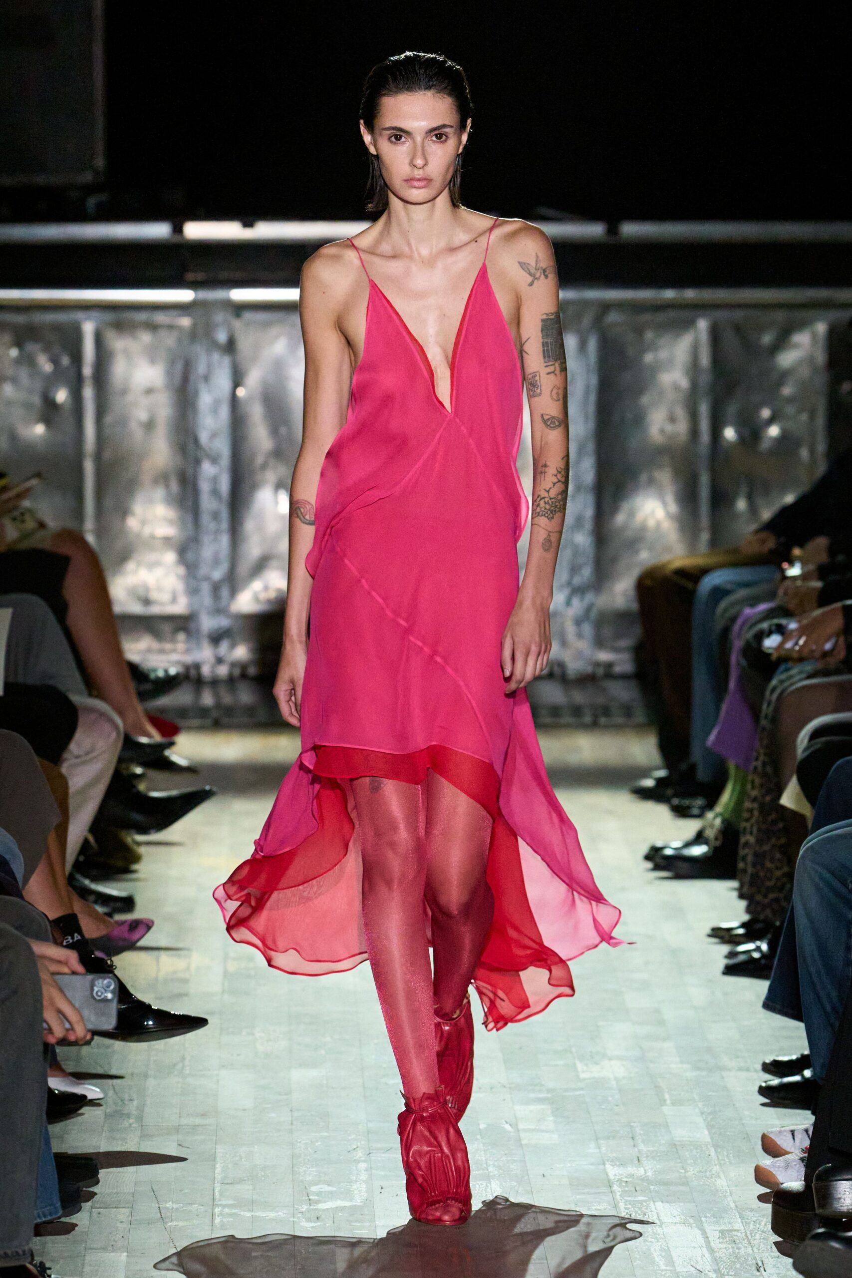 Hot-pink chiffon slip dress, plunge slit neckline and handkerchief hem. Shimmering rose tights, almost lacquered under the lights. Matching ruched ankle boots with a soft gathered opening. Crossing a hotel ballroom after midnight with your shoes in hand.