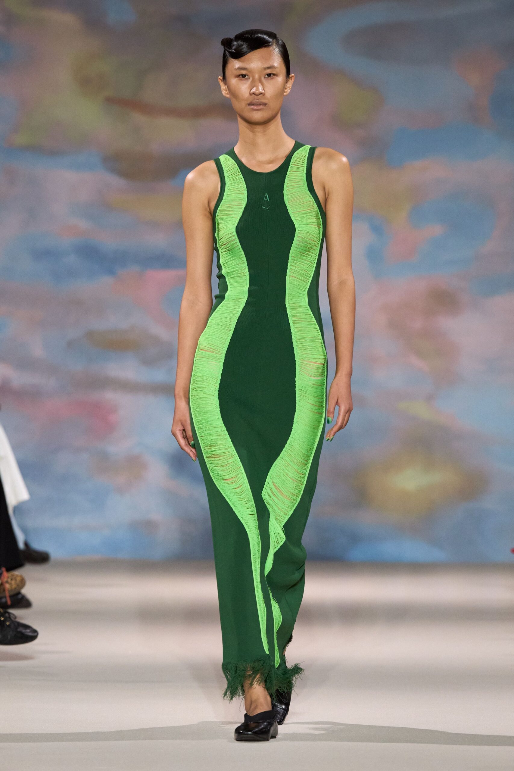 Forest green column knit, traced by acid-lime ladders that ripple into a loose front streamer. Black square-toe flats with a low, blunt heel. Greenhouse walkway after rain, brushing past wet leaves and warm glass.