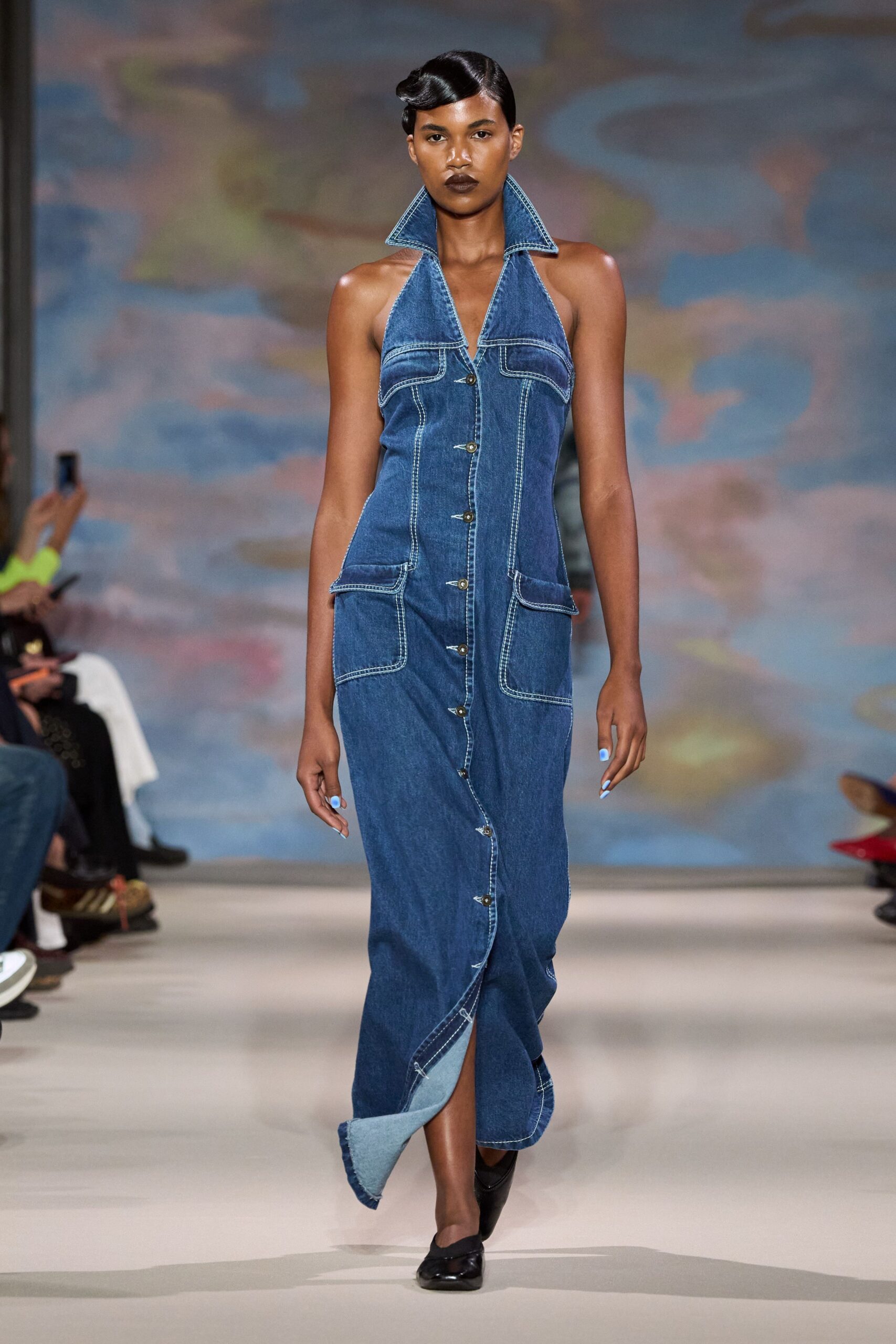 Dark-wash denim halter dress with a popped collar and contrast topstitching. Black flats, square at the toe. Walking home from a county fair after the lights cut out.