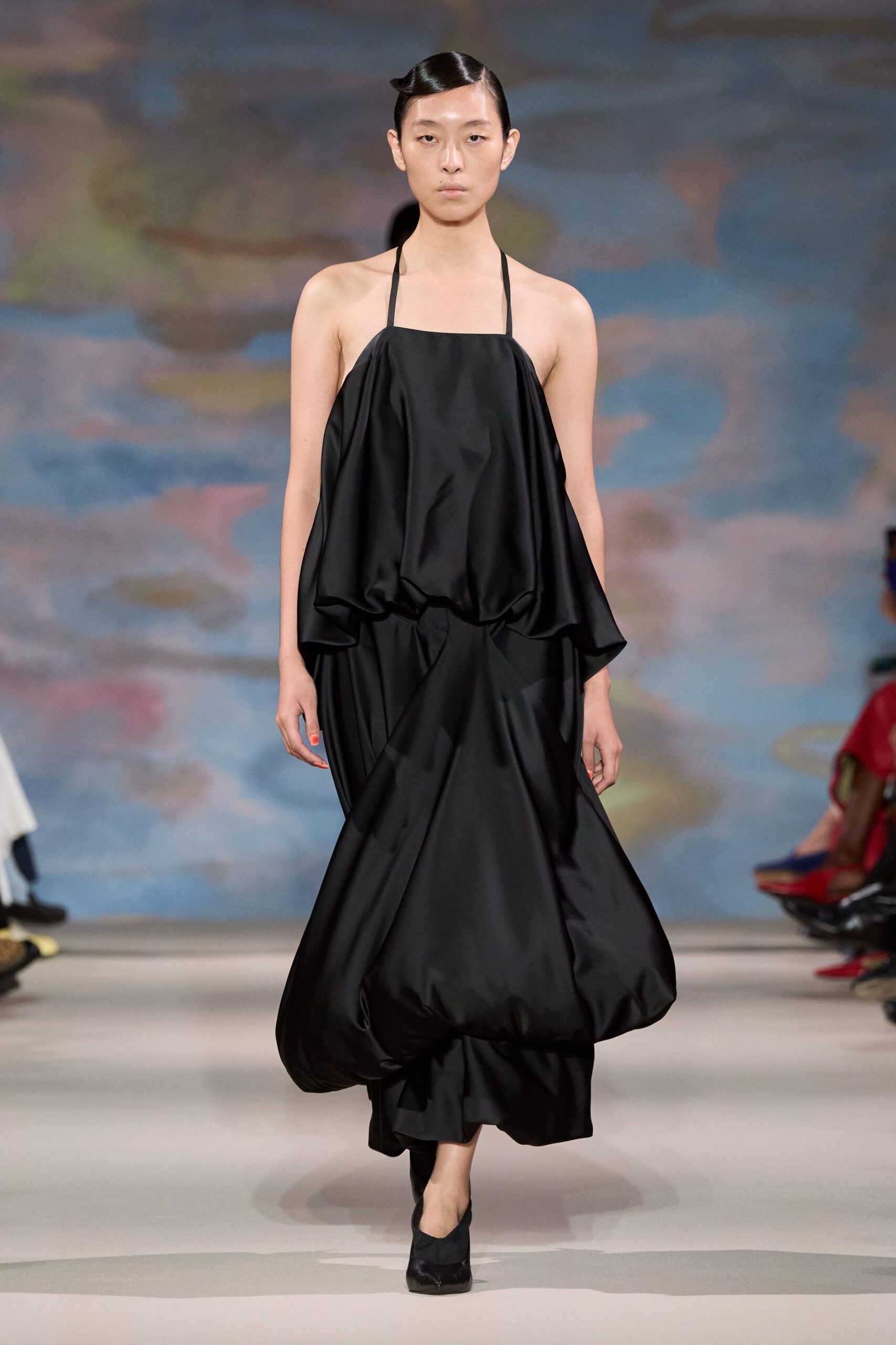 Black halter dress in crisp satin, blouson bodice collapsing into a puffed hem. Black pumps with a squared vamp. Whatever you wear to cross a hotel lobby at dawn unnoticed.