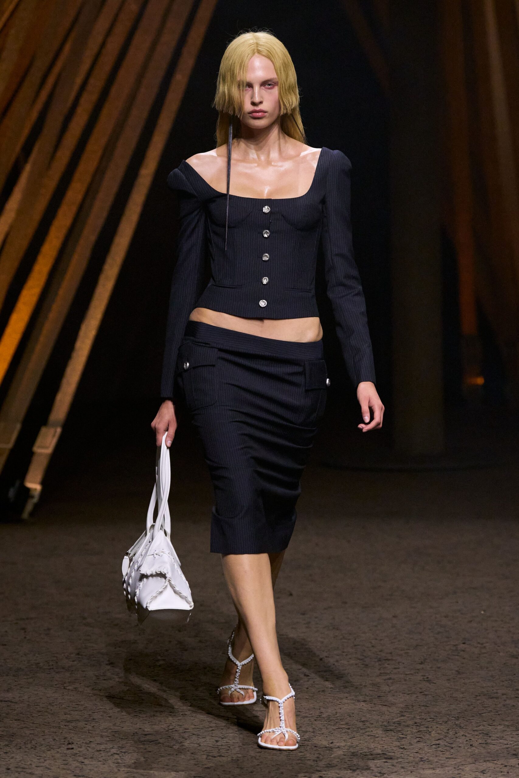 Navy pinstripe top with a square neck and silver coin buttons. Matching pinstripe pencil skirt, cut low on the hip with flap pockets. White leather tote with ruched seams and looped handles. White rope-strap thong sandals with a square toe. Walking into a hotel bar before your room is ready.