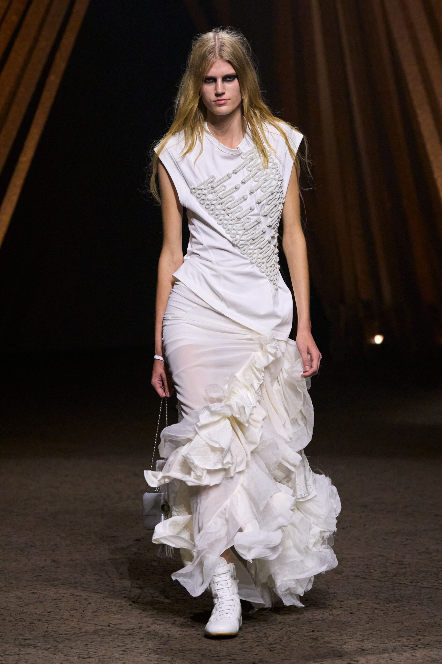 White cap-sleeved dress, diagonal frog fastening over a twisted bodice and clouded organza ruffles. Mini white bag on a fine chain strap. White leather high-tops, laces pulled flat to the toe. Walking across chapel gravel after the ceremony slipped into dawn.
