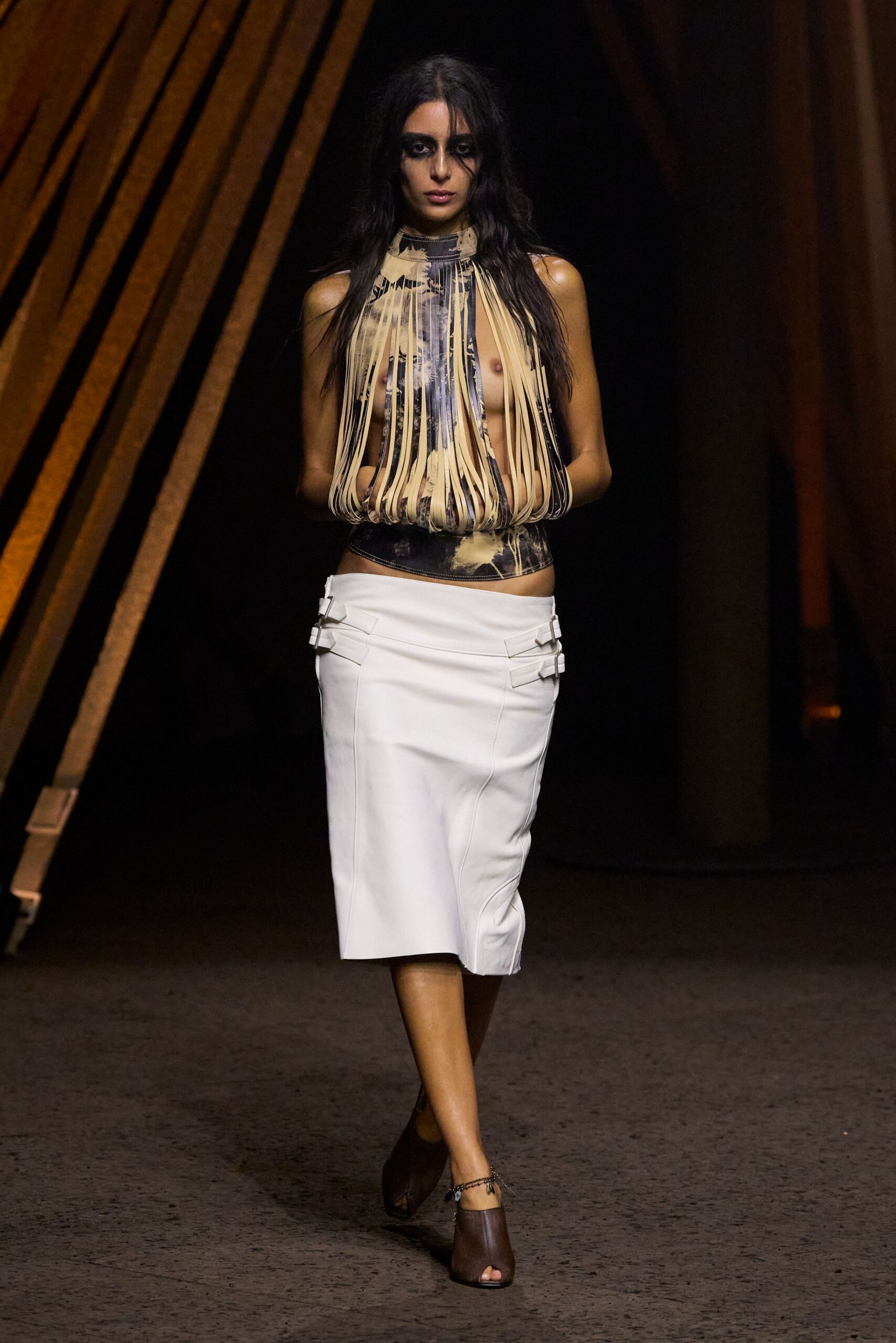 Nude and charcoal printed halter, cut into long fringe strips over the chest. White leather pencil skirt with side buckle tabs and curved seaming. Brown peep-toe mules. Fine chain anklet catching at one shoe. For crossing a hotel lobby at dawn with last night's makeup still on.