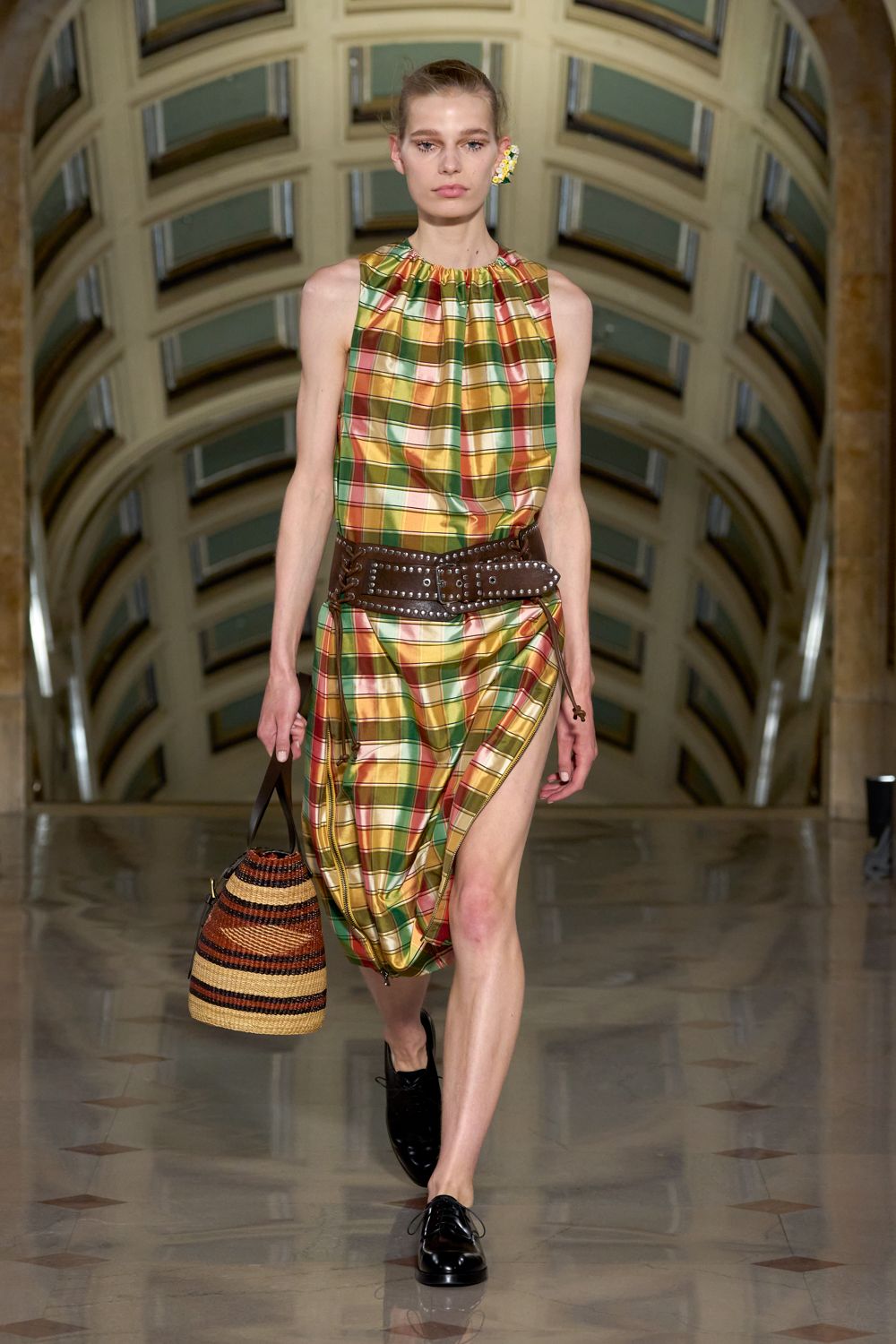 Glossy plaid halter dress, tunnel-pulled into a high zippered slit. Wide brown leather belt, studded and laced at the side. Striped raffia bucket bag with dark leather handles. Black derbies, mirror-shined. Tiny daisy ear cuff. For buying apricots and hard cheese under a station dome at noon.