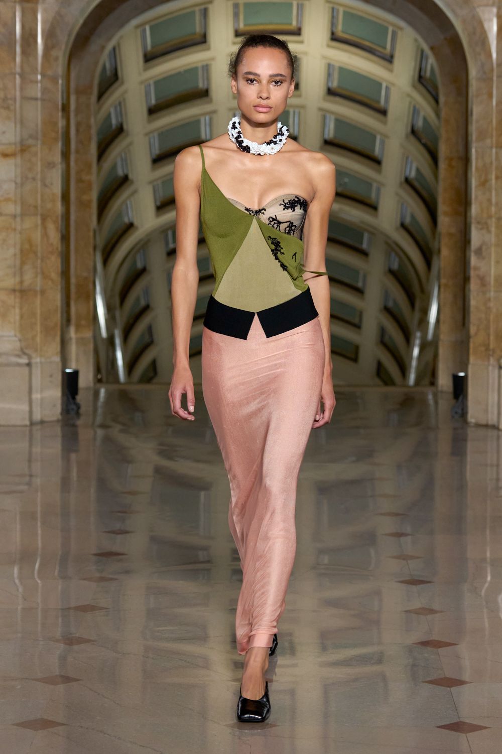 Ruffled white collar necklace speckled with clustered black beads. Asymmetric olive camisole pieced with taupe mesh and black floral applique. Blush satin column skirt, creased and skimming into the shoe. Black square-toe pumps. Crossing a marble atrium after sending the difficult text at lunch.