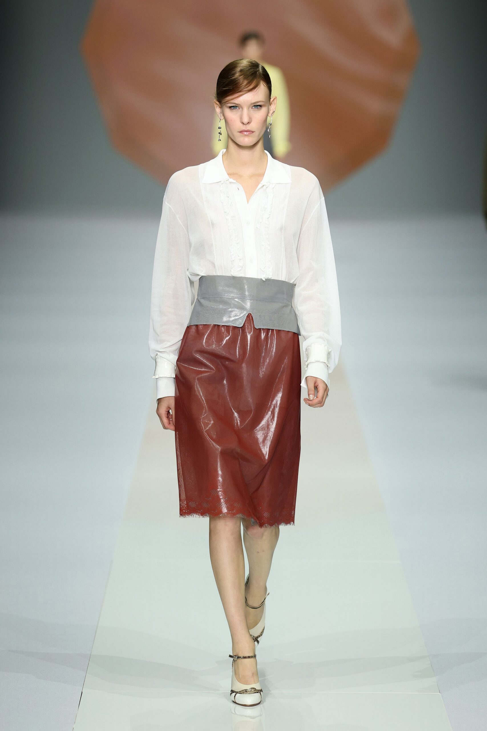 Sheer white blouse with pintucked panels and soft ruffles beside the placket. Wide dove-grey leather yoke wrapping the hips, split at center front. Russet patent skirt with a scalloped lace hem peeking underneath. Cream pumps with narrow snakeskin ankle straps. Whatever you wear to read old letters in a cold sunroom.