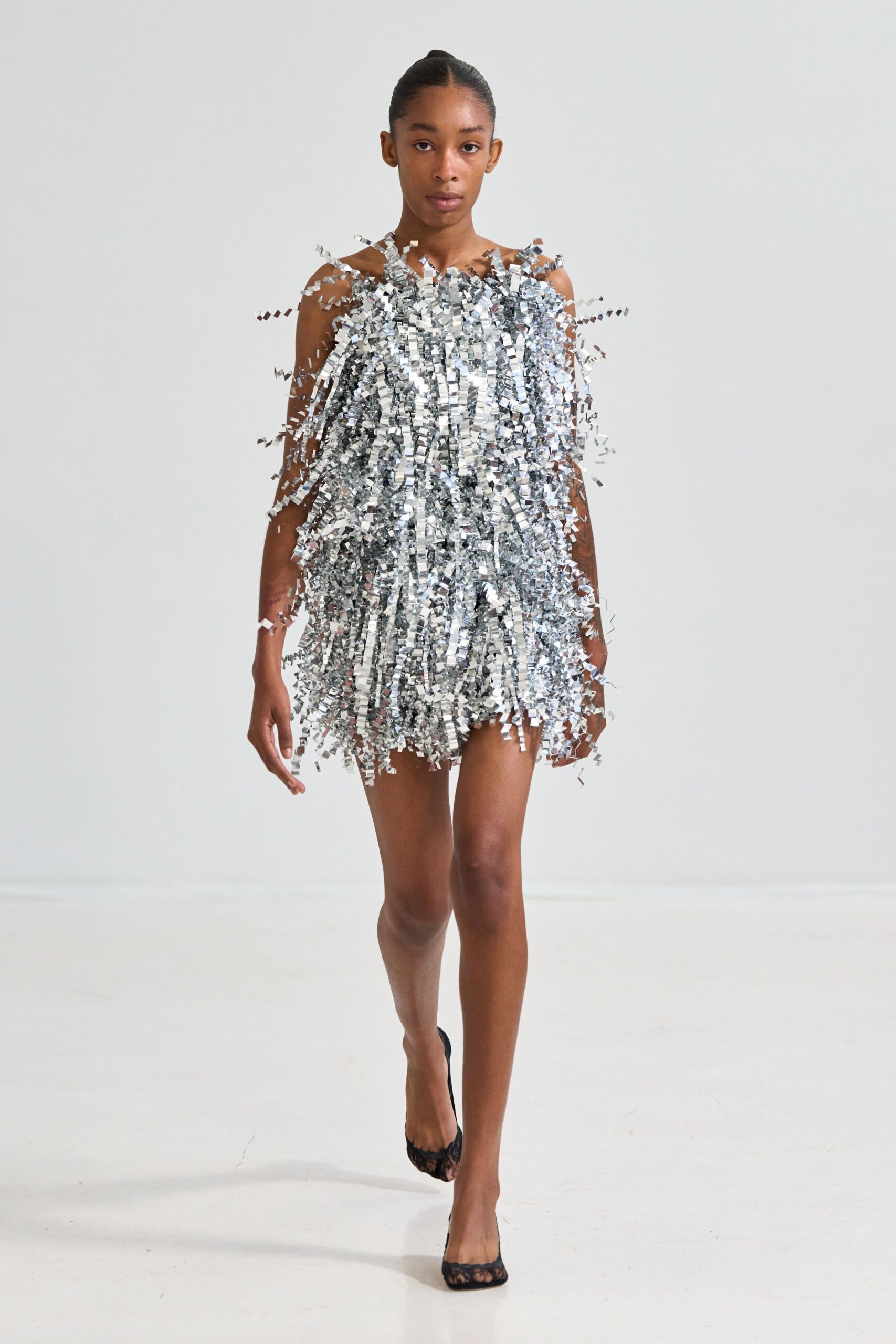 Silver tinsel shift, shoulder straps nearly lost under dense foil fringe. Black lace pumps with a peep toe. Crossing the office carpet after the holiday party emptied into dawn.