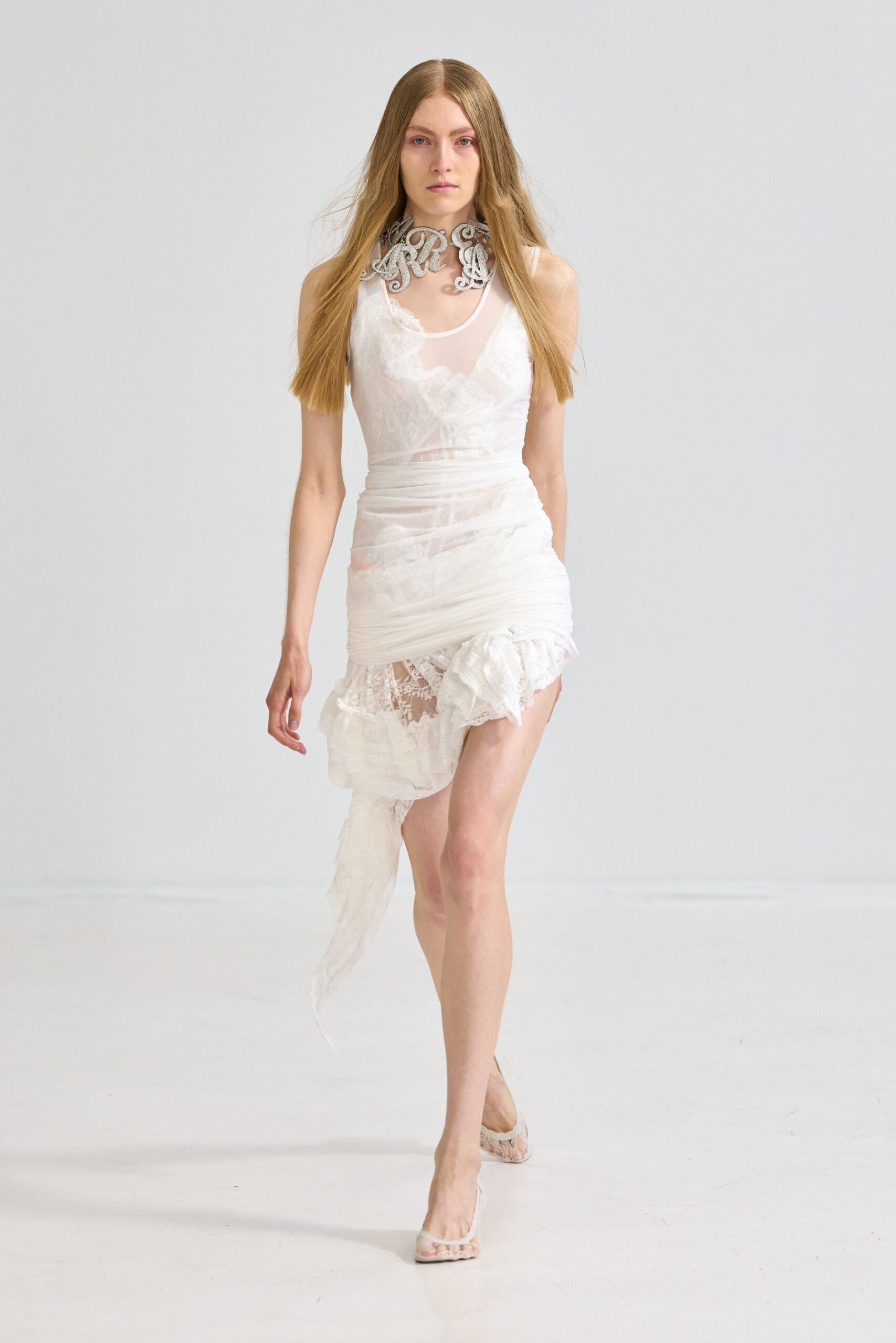 Silver scrollwork collar, thickly beaded and cinched close at the throat. Sheer white mesh dress over lace slips, ruched tight through the hips. White lace mules with a narrow pointed toe. Whatever survives the morning after a courthouse wedding.