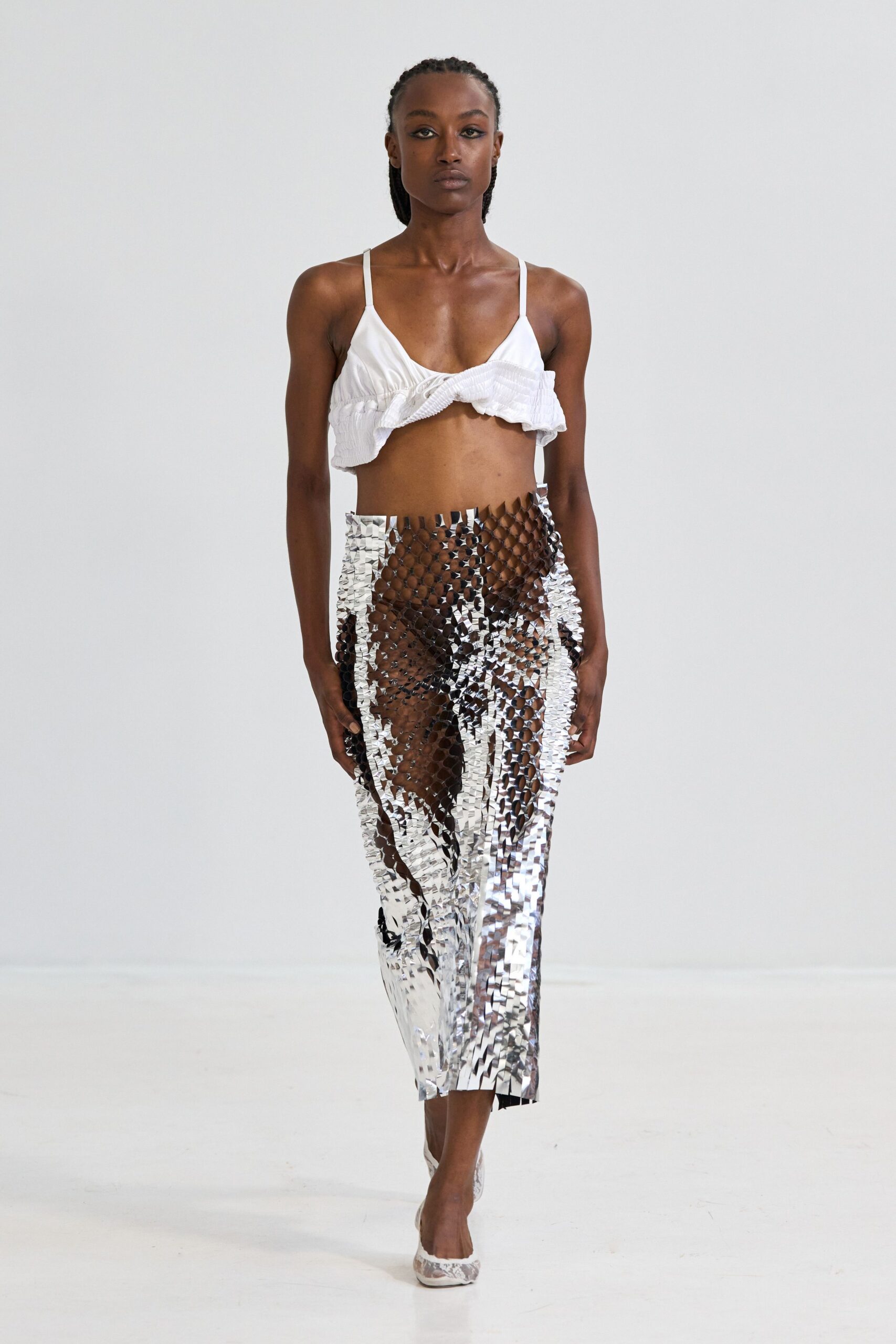 White cotton bralette with a twisted ruffle skimming one side. Transparent silver paillette tube skirt, long strips hanging uneven at the shin. White brocade pumps. Walking along the pier after dark with tinfoil streamers caught on the rail.