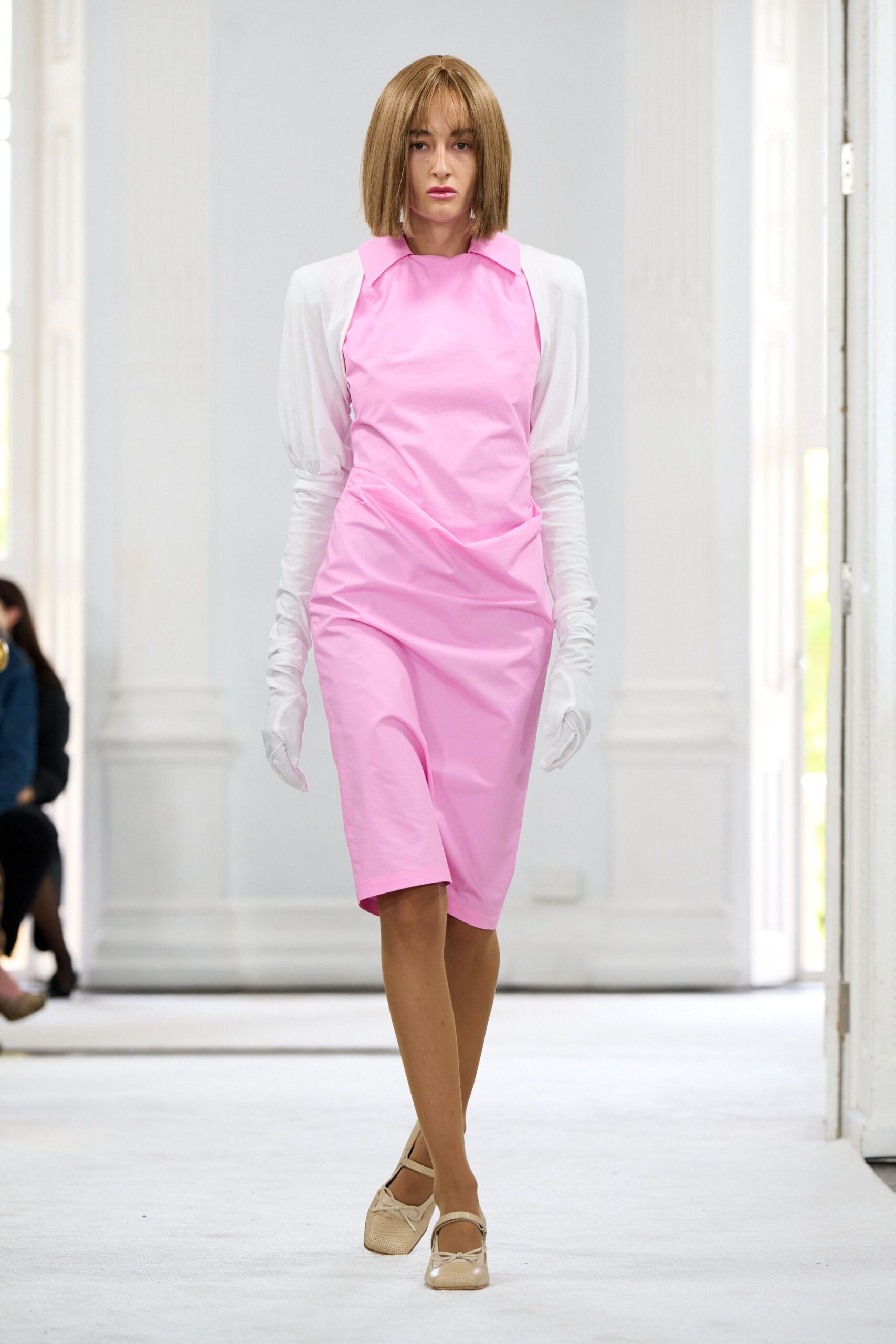 Bubblegum pink sheath dress, crisp folded collar and a twisted hip drape. White jersey opera gloves ruched along the forearms. Cream mary jane flats with perforated leather and tiny bow knots. Walking the long corridor to a courthouse wedding at noon.
