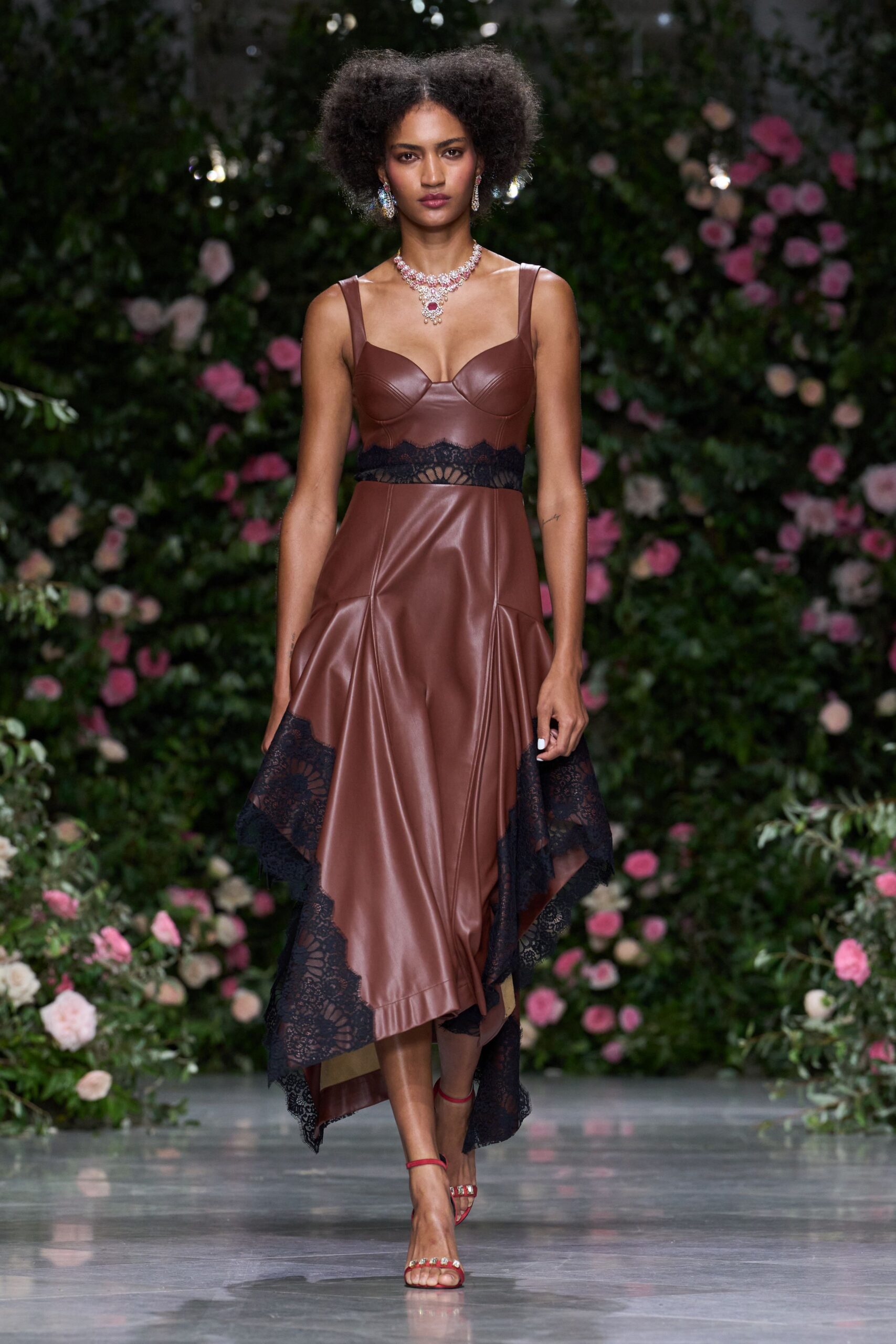 Chestnut leather dress with balconette seaming and black lace spliced at the waist and hem. Red ankle-strap sandals with crystal-set toe bands. Clustered stones around a drop ruby pendant. Mismatched chandelier drops. Garden wedding after midnight, heels catching on the gravel path.