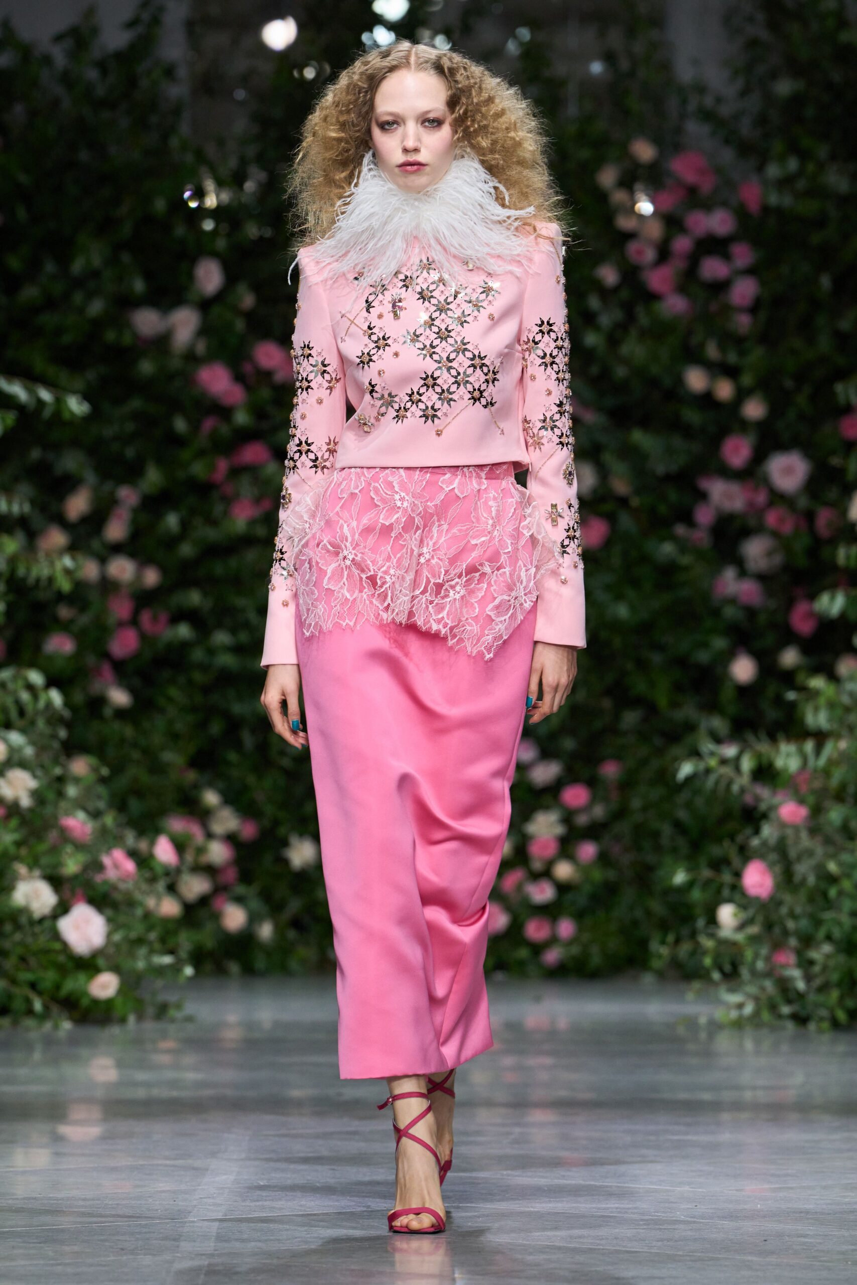 Cloud of white plumes circling the throat. Shell-pink long-sleeve top scattered with mirrored starburst embroidery. Sheer floral lace peplum jutting out at the hips. Bubblegum satin column skirt, softly creased through the shin. Fuchsia wrap-strap sandals. Crossing a winter garden after the wedding guests have gone in.