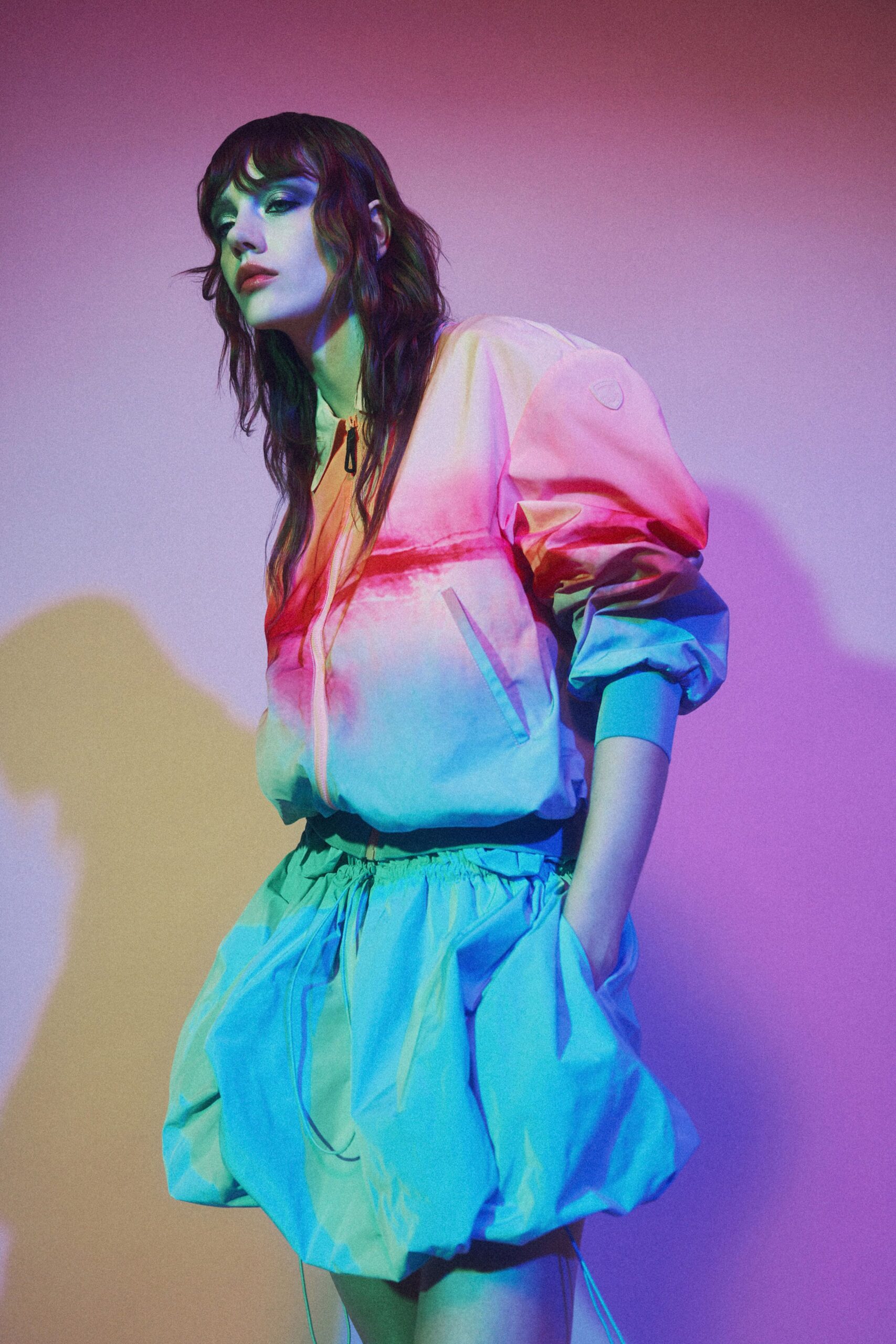 Blush nylon jacket with puffed sleeves and a black ring zip pull. Mint nylon balloon shorts, gathered waist and inflated hems. Arcade lights bleeding through the laundromat windows after midnight.