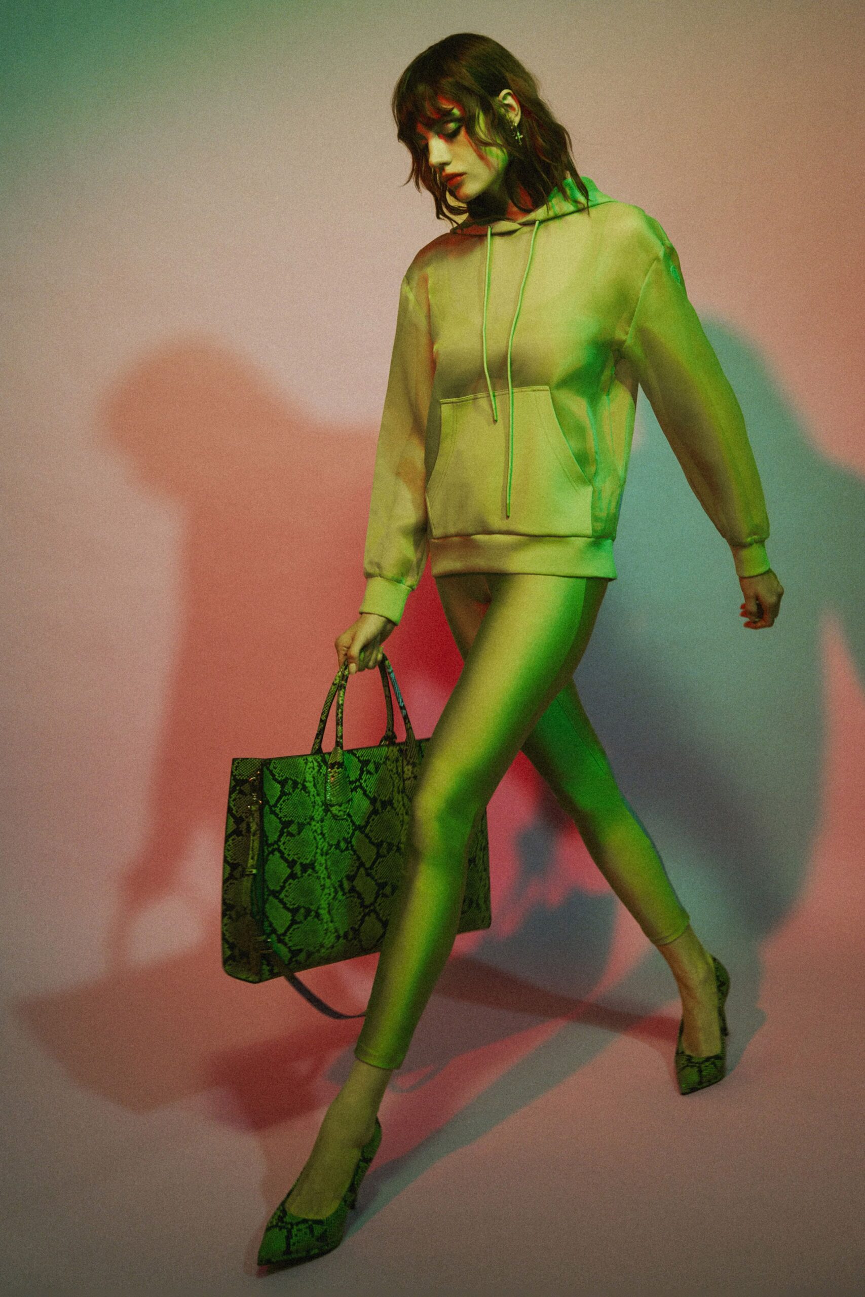 Cream jersey hoodie with long drawstrings and a squared kangaroo pocket. Second-skin cream leggings, nearly merging into the bare leg. Large python-print tote with slim rolled handles. Matching python pumps, sharply pointed. For crossing a hotel lobby when you want the room key fast.