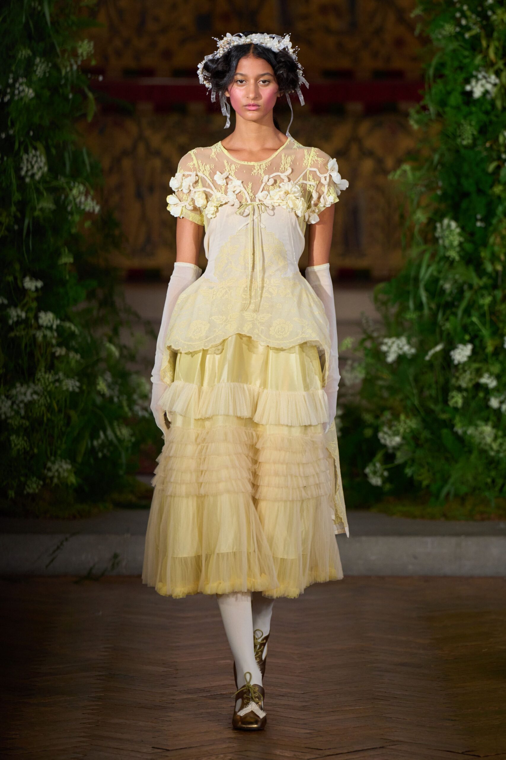 Pearled blossoms and wired petals with narrow ribbon ties at the ears. Buttercream tulle dress, sheer yoke blooming with raised appliqued flowers. Cloudy sheer gloves to the upper arm. Opaque ivory stockings. Bronze lace-up pumps with white scalloped inserts. For walking back from the orangery after the cake has been cut.